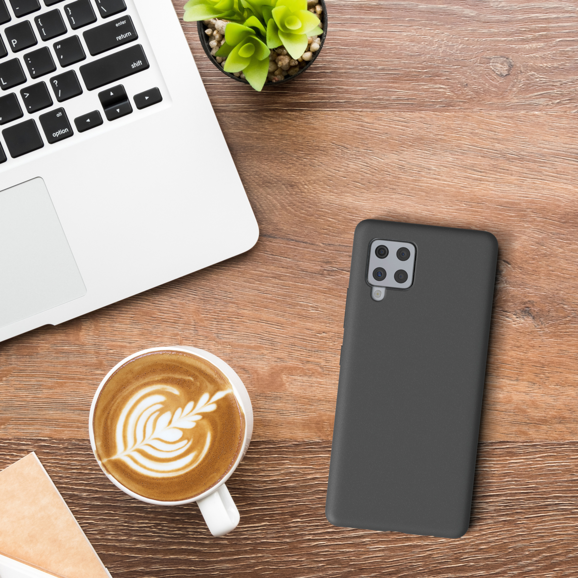 Eine schwarze Handyhülle auf einem Holztisch. Ein Laptop und eine Kaffeetasse sind sichtbar.