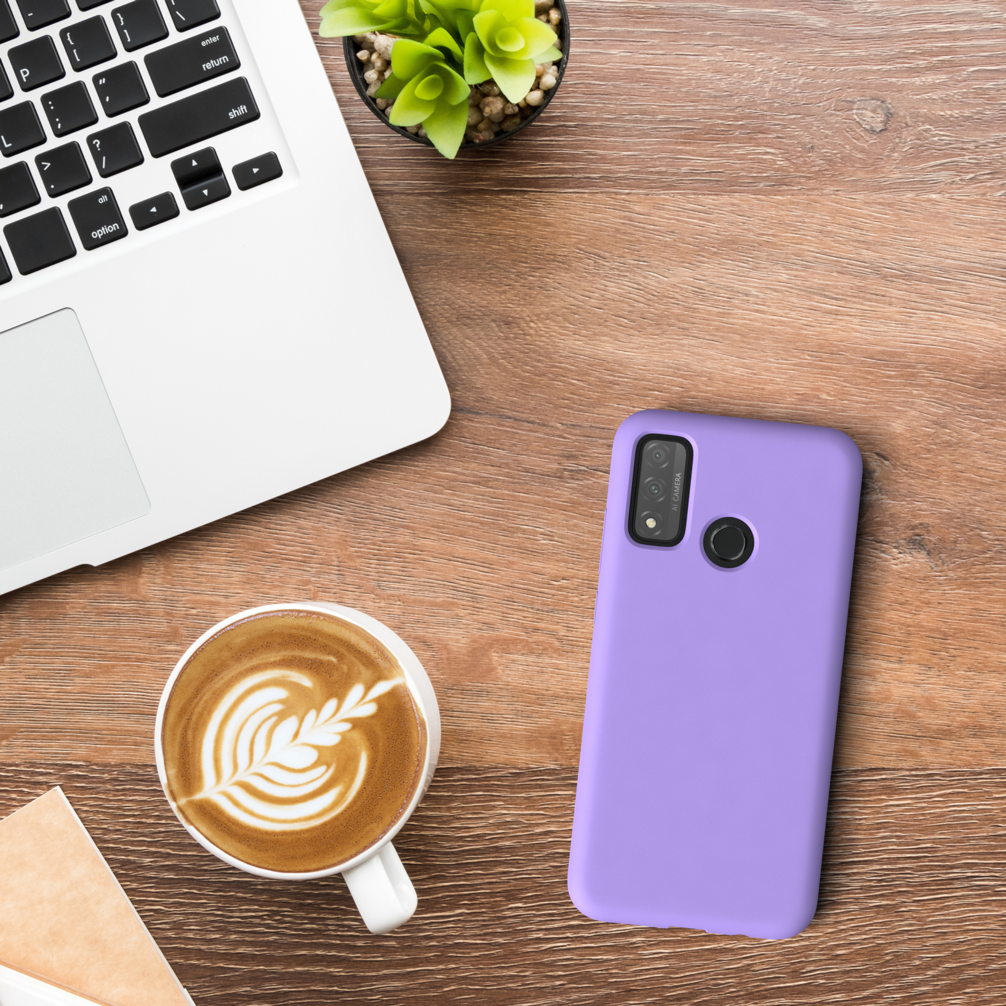 Laptop, Kaffeetasse und lilafarbene Handyhülle auf einem Holzschreibtisch. Eine kleine Pflanze ist auch sichtbar.