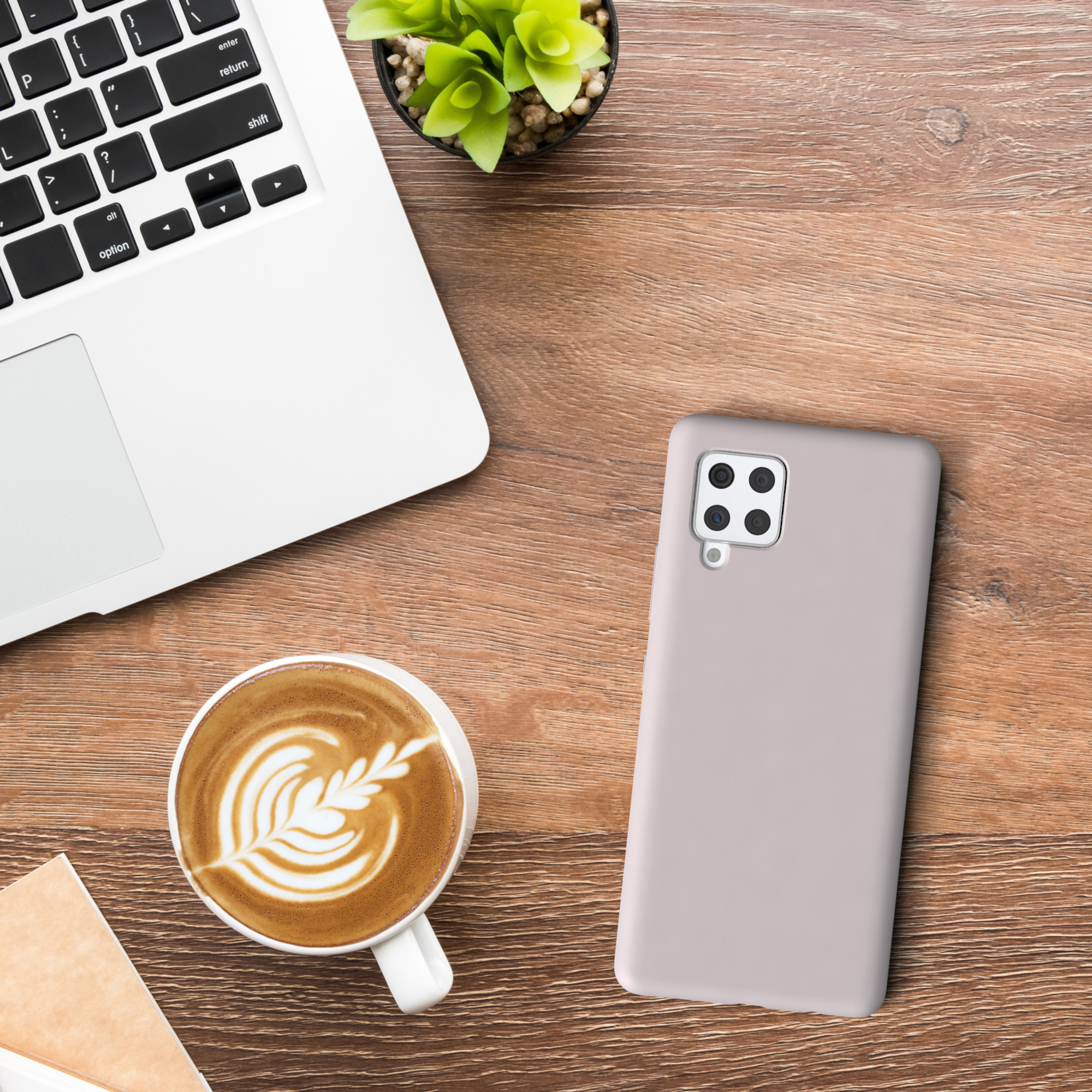 Laptop, Kaffee, Handyhülle und eine Pflanze auf einem Holztisch. Die Handyhülle befindet sich neben dem Laptop.