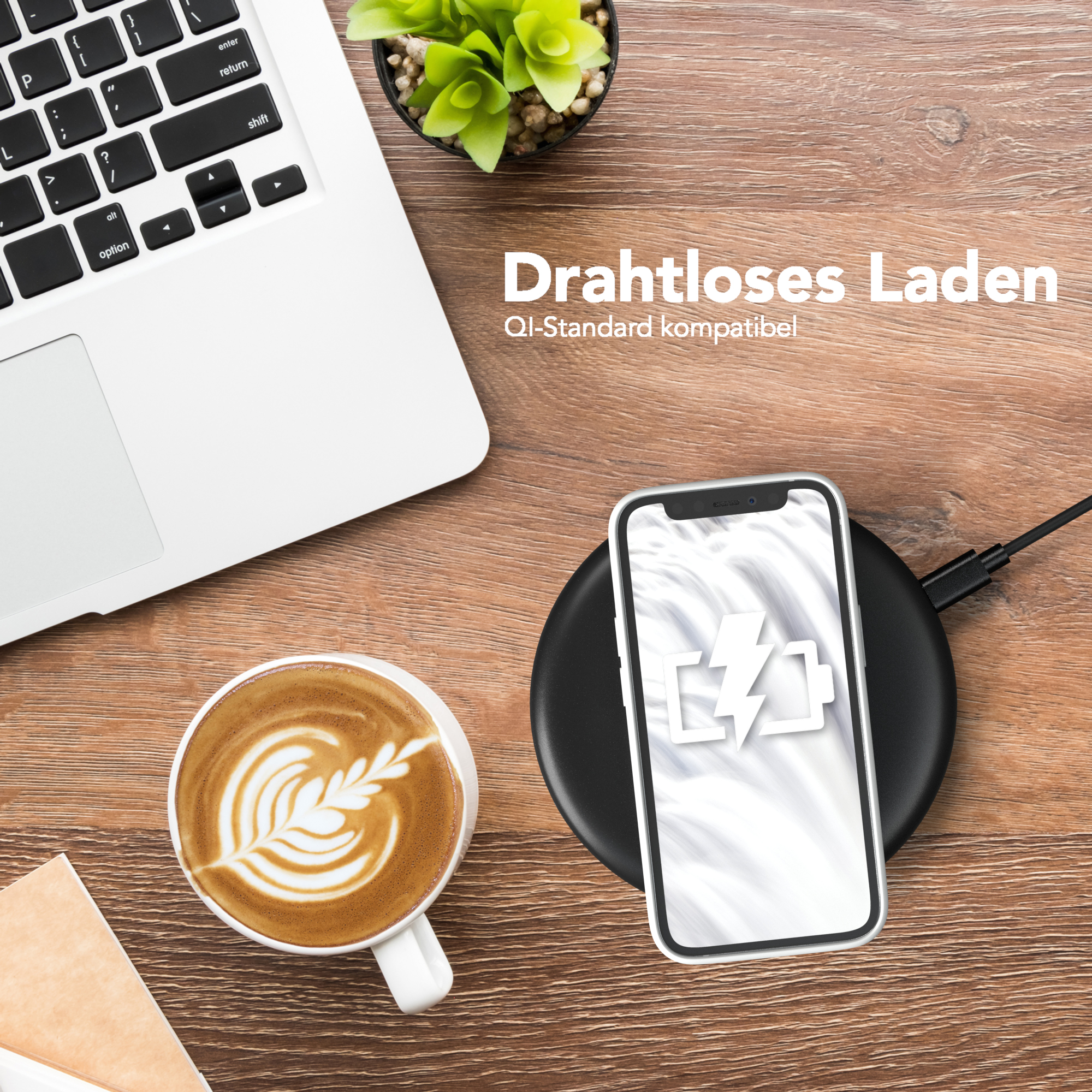Ein Telefon wird kabellos auf einem Ladepad geladen. Daneben ein Laptop und eine Tasse Kaffee.