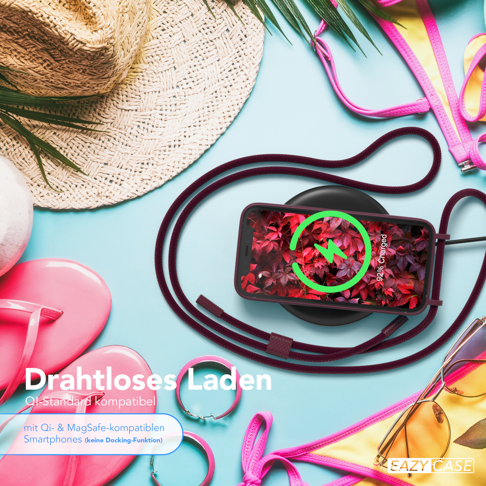Telefon wird kabellos auf einem Pad geladen, mit Lanyard. Zubehör: Flip-Flops, Hut und Sonnenbrille auf blauem Untergrund.