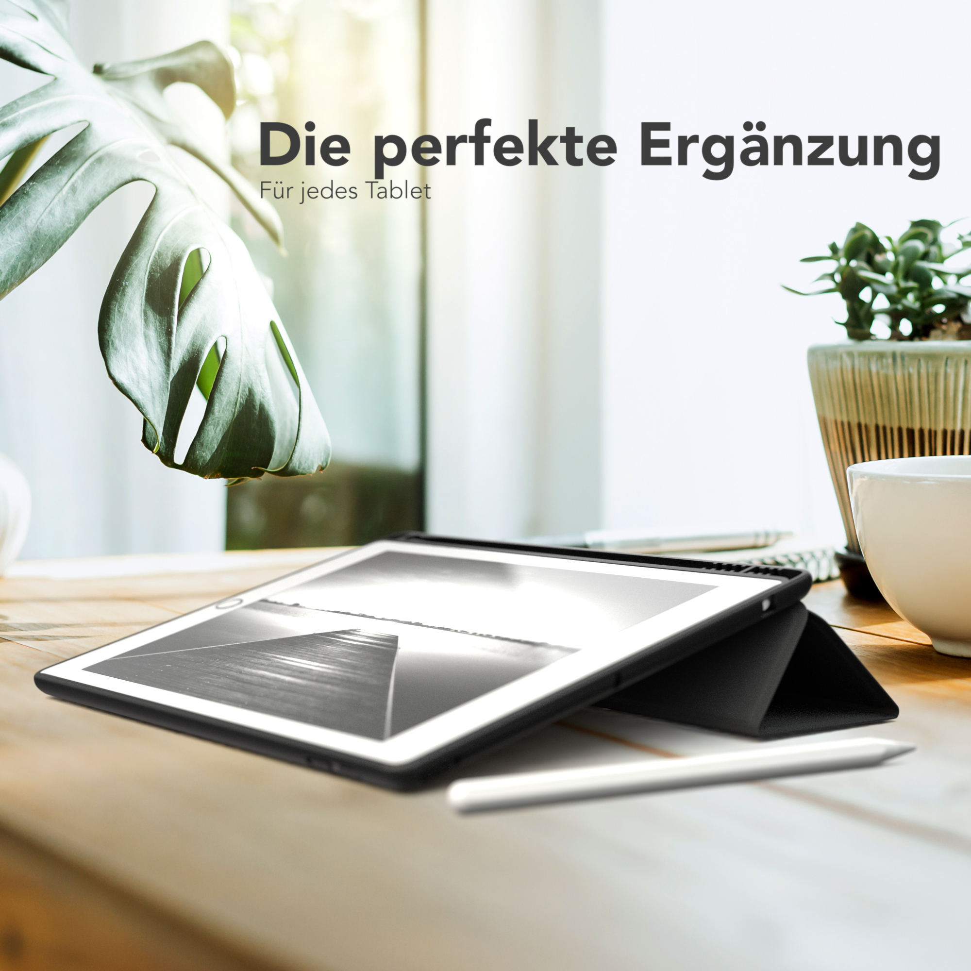 Ein Tablet auf einem Holztisch mit einem Stift, mit einer Pflanze und einer Tasse.