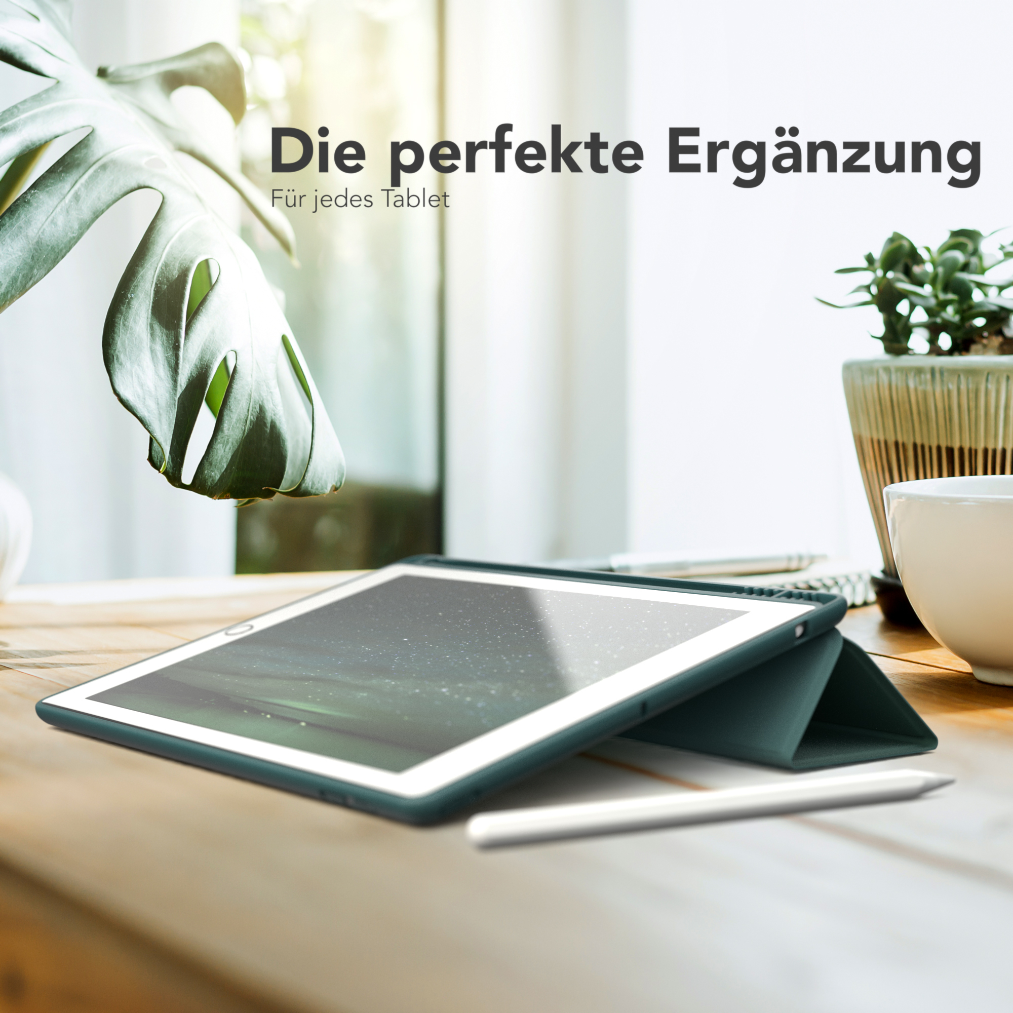 Tablet in einer grünen Hülle auf einem Holztisch mit Stift und Pflanze.