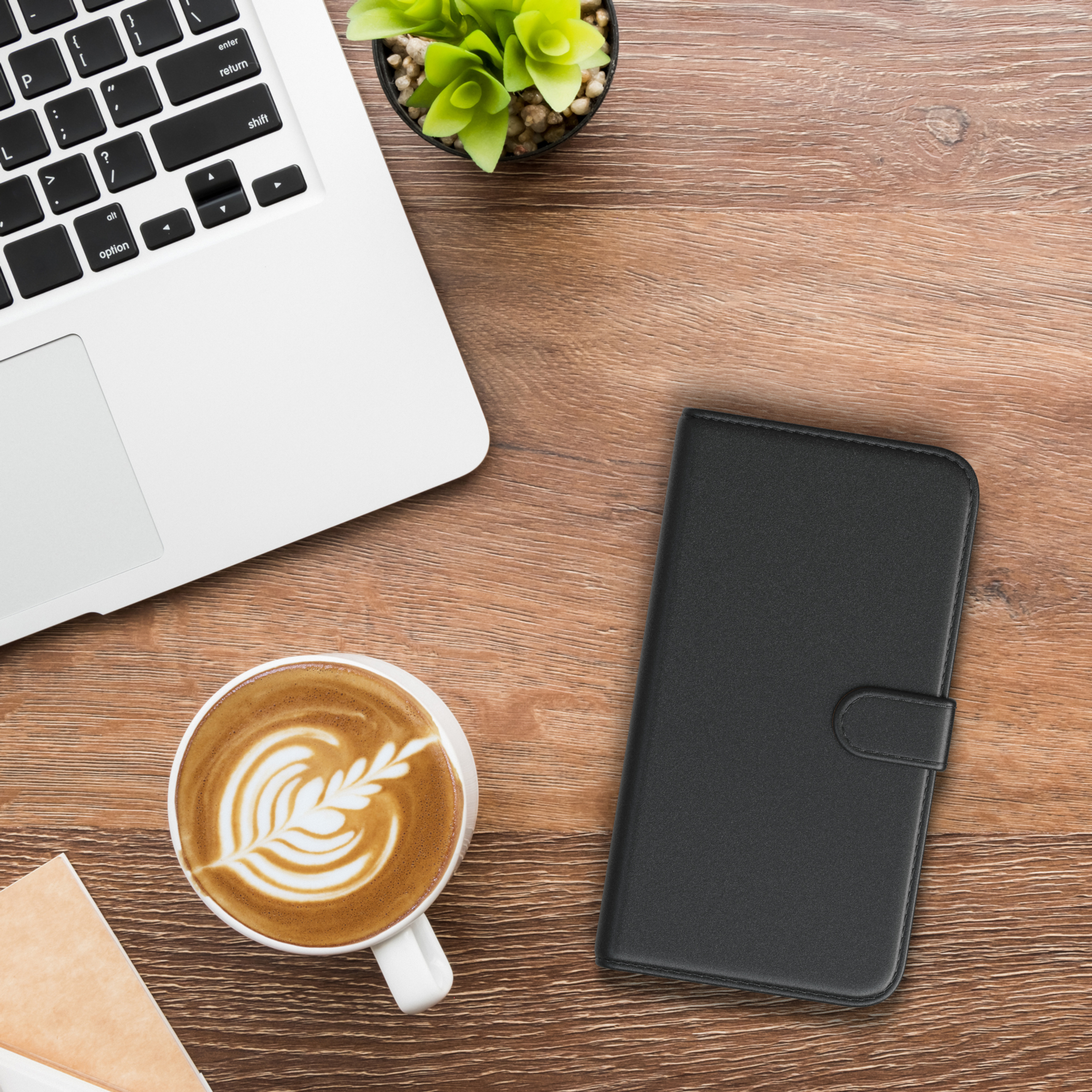 Laptop, Kaffee und eine Handyhülle auf einem Holztisch, Draufsicht.