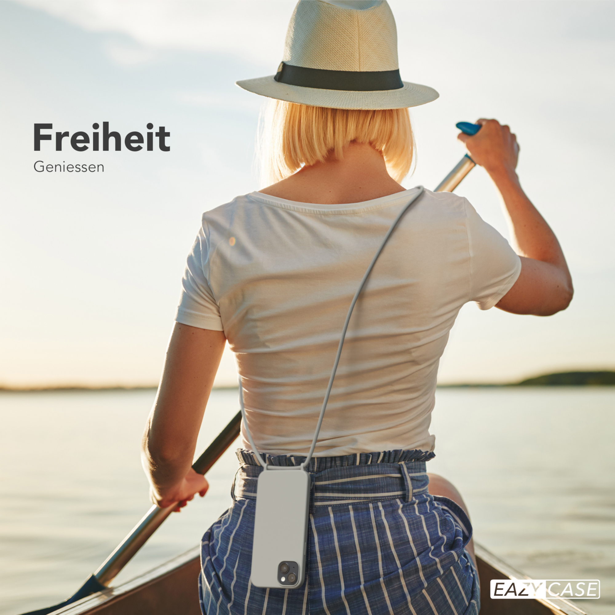Eine Frau rudert ein Boot auf einem See und trägt ein Telefon-Lanyard. Die Sonne scheint.