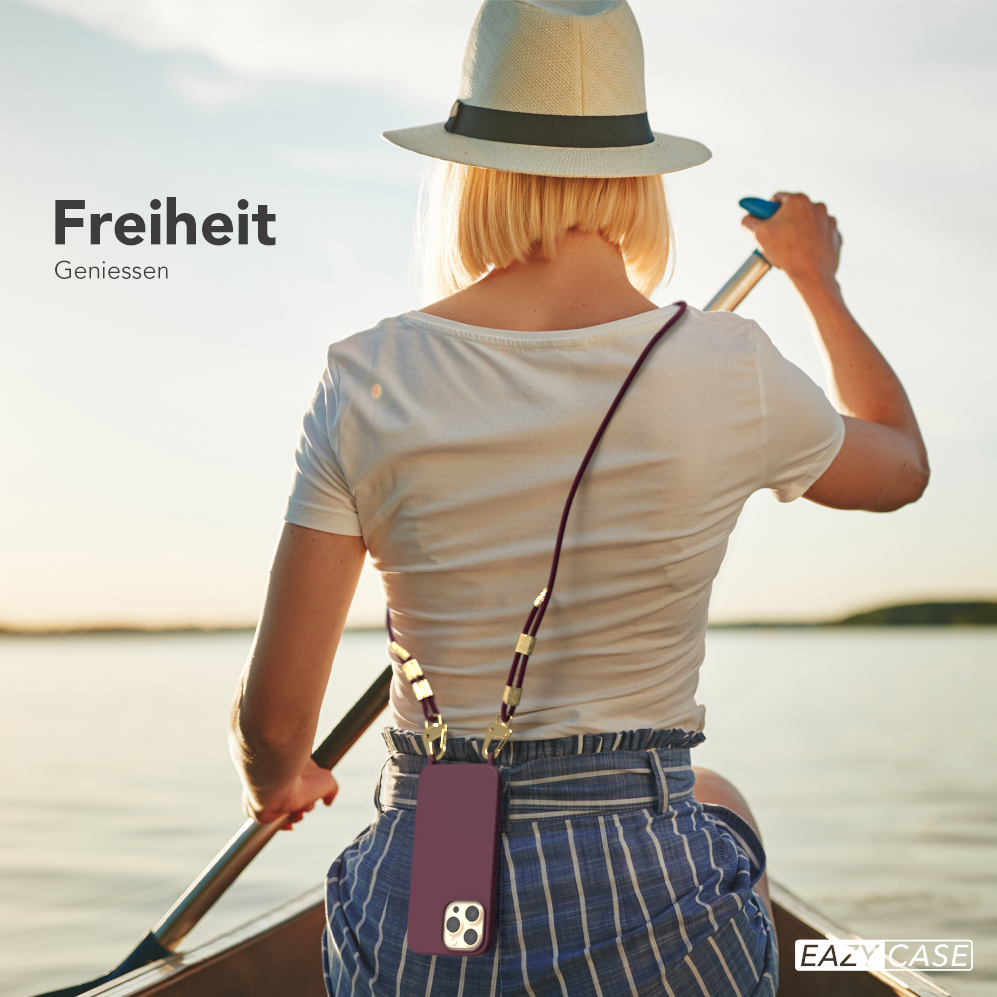 Frau rudert Kanu. Telefon mit Band hängt um den Hals. See und Sonne im Hintergrund.