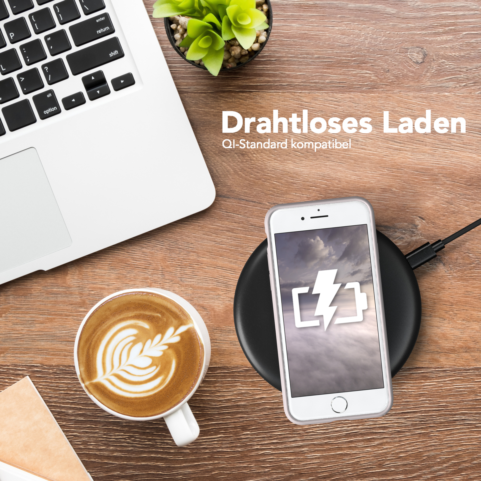 Laptop, Telefon auf kabellosem Ladegerät, Kaffee und eine kleine Pflanze auf Holzoberfläche.