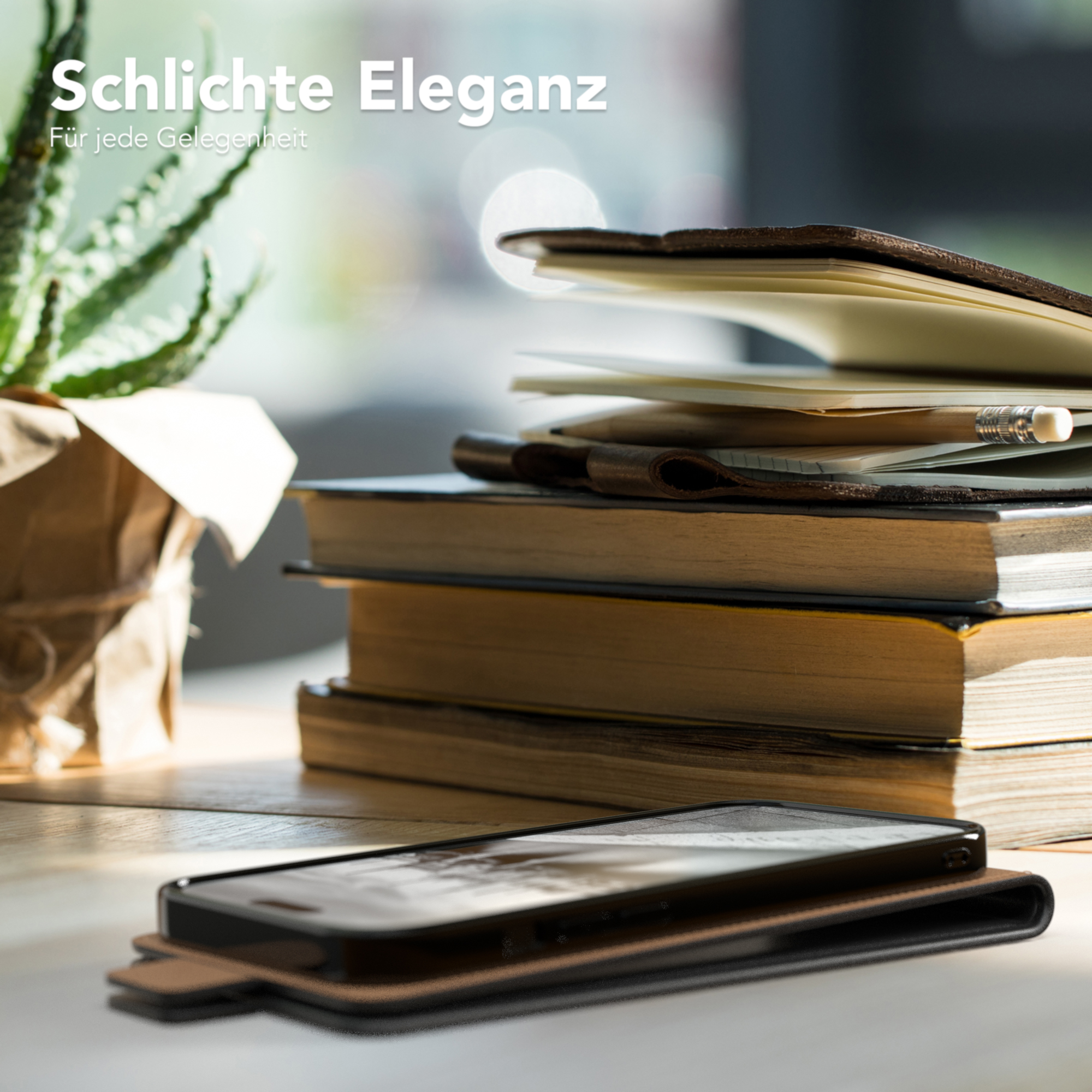 Telefon in Hülle auf dem Schreibtisch. Bücher, Pflanze und Bleistift sichtbar.
