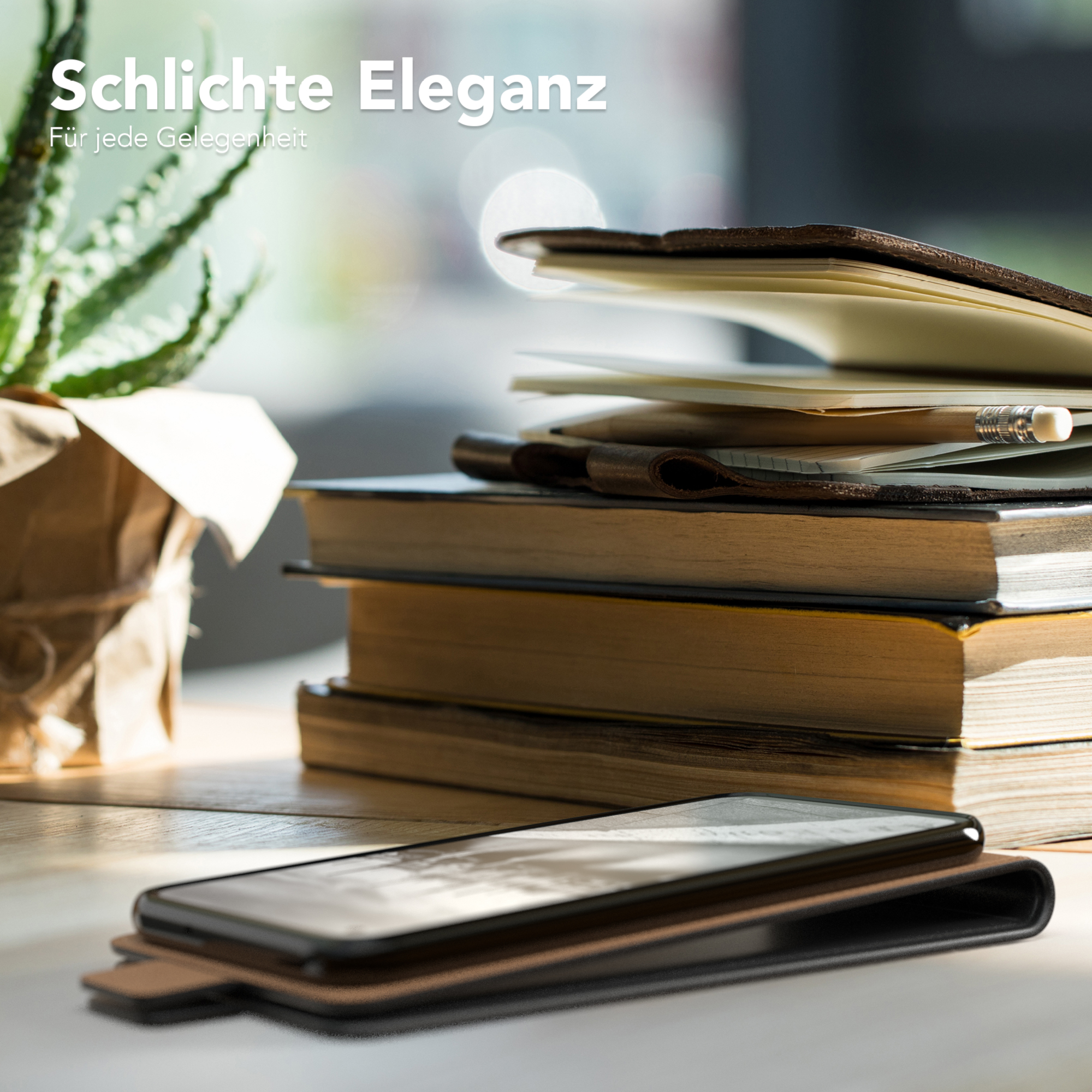 Notizbuch, Bleistift und Telefon auf einem Holztisch mit einer Pflanze im Topf. Bücher sind gestapelt.