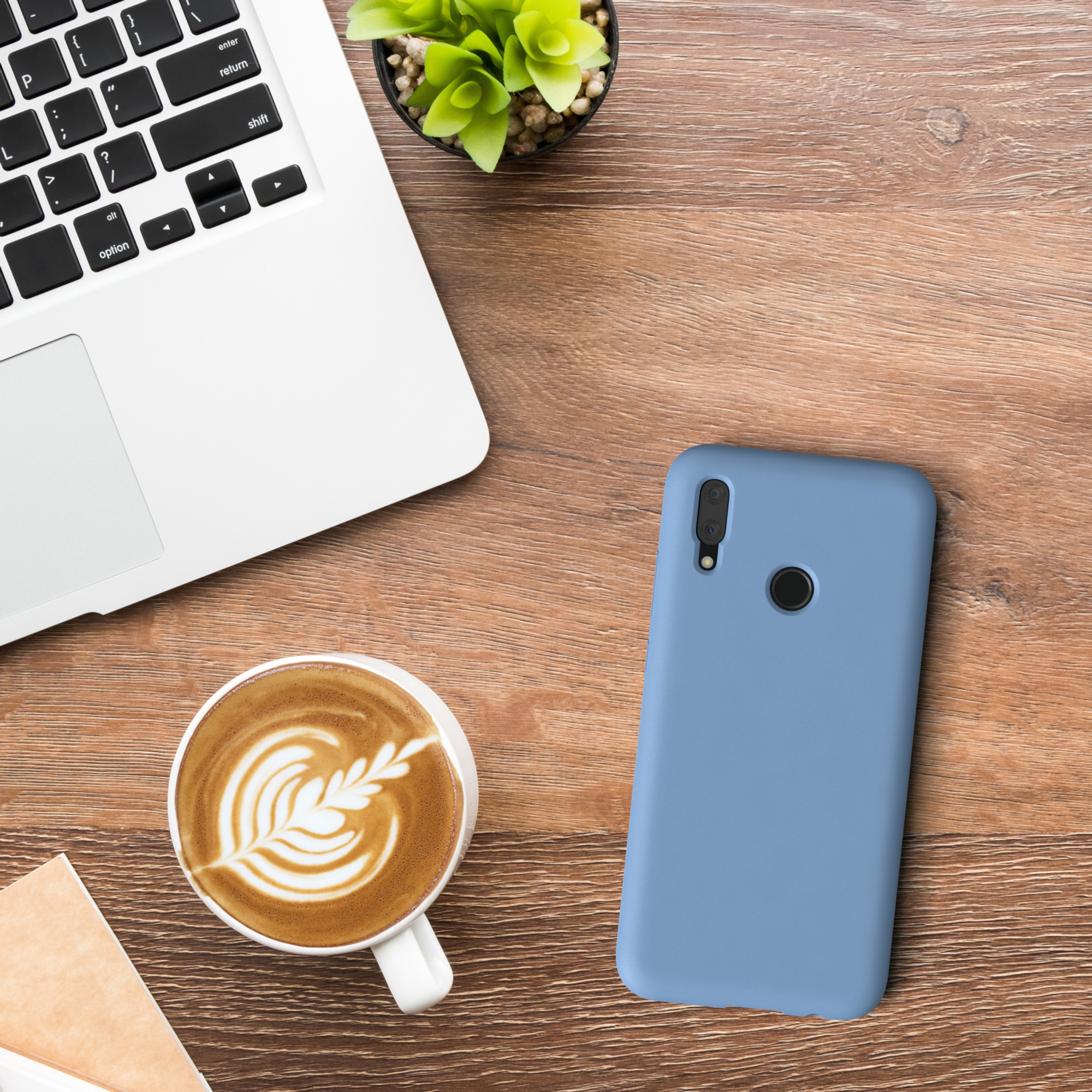 Laptop, Kaffeetasse mit Latte Art und eine blaue Handyhülle auf einem Holzschreibtisch.