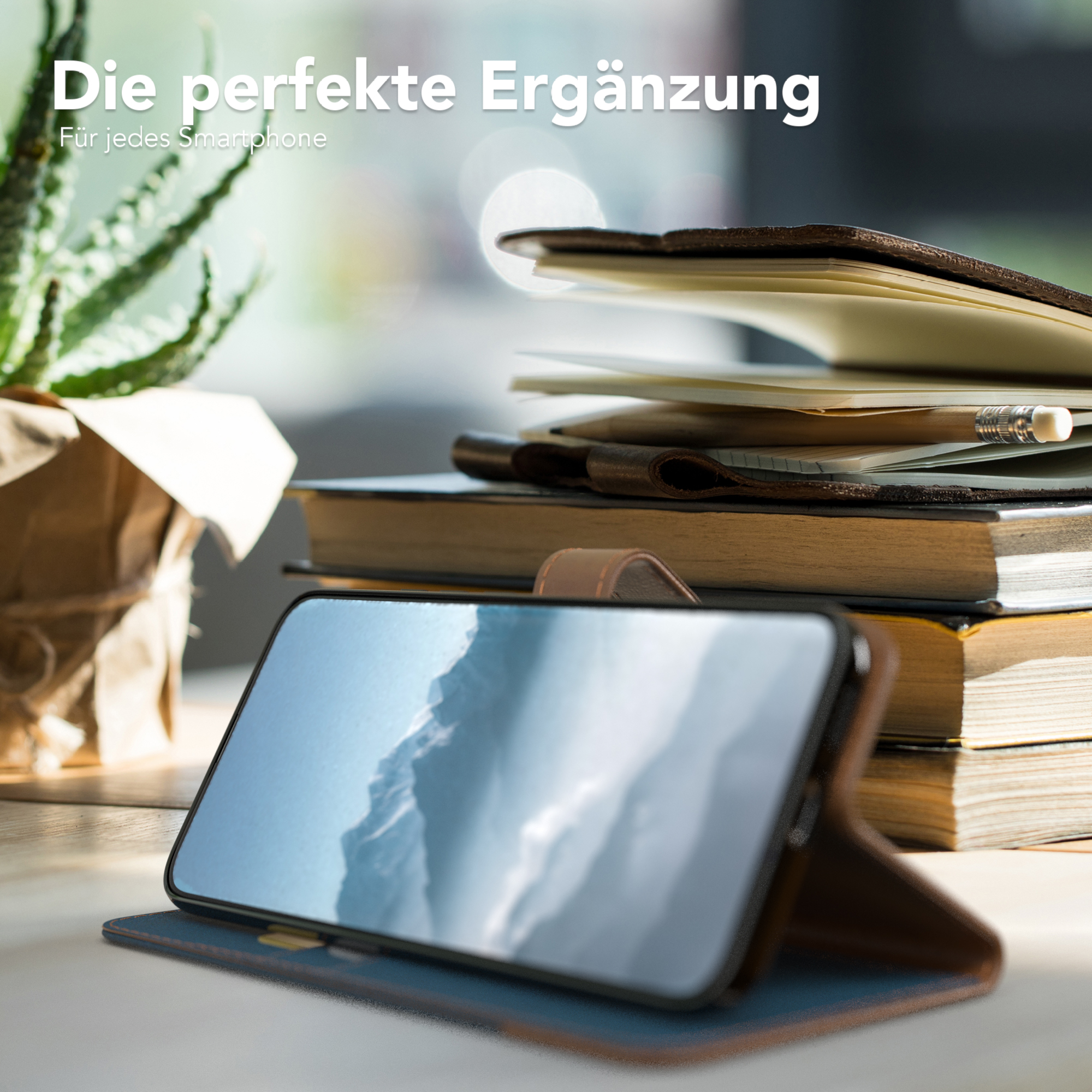 Smartphone in einer braunen Hülle. Bücher und eine kleine Pflanze stehen im Hintergrund auf einem Tisch. Der Telefonbildschirm ist sichtbar.
