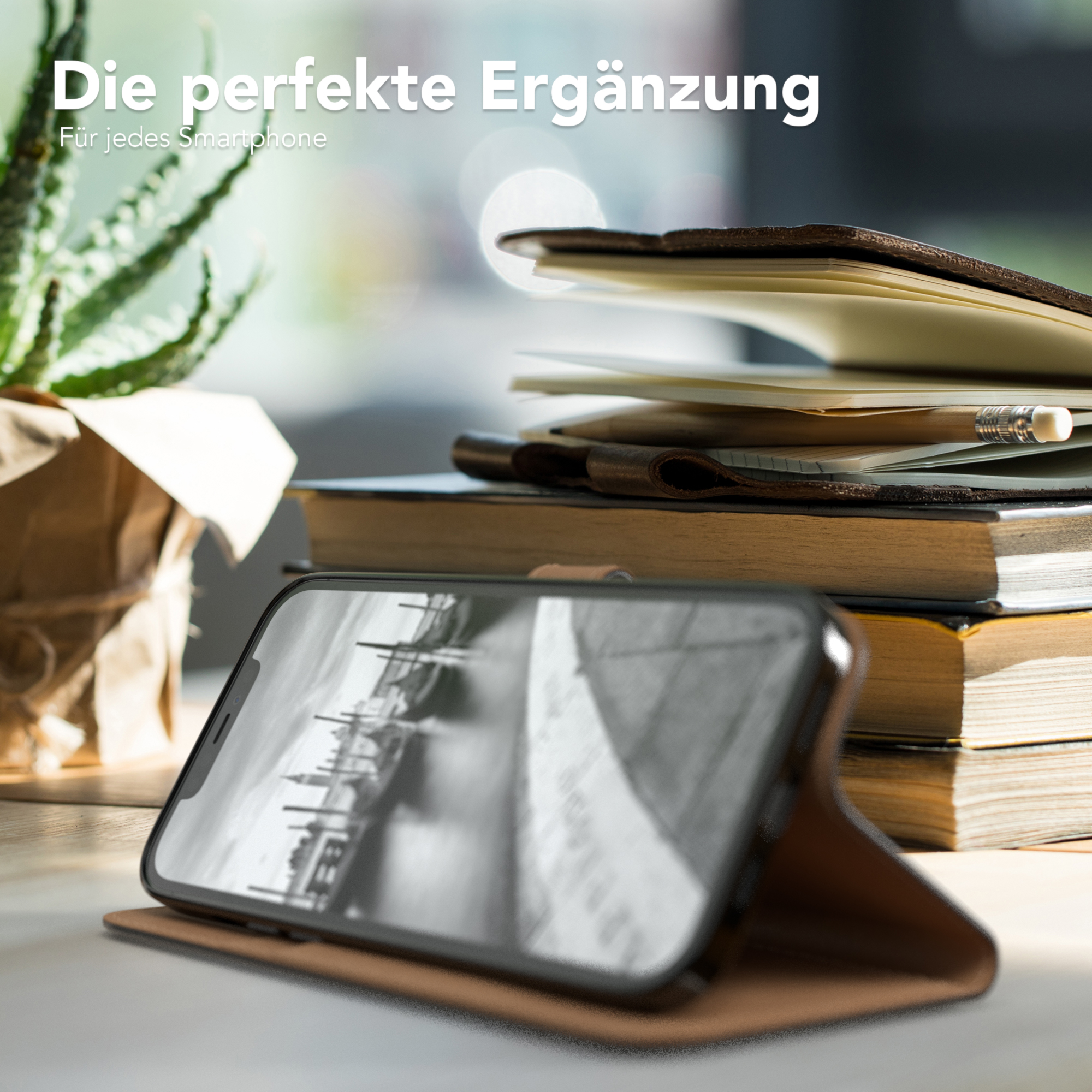 Ein Smartphone in einer braunen Hülle, geöffnet. Bücher und eine Pflanze im Hintergrund.