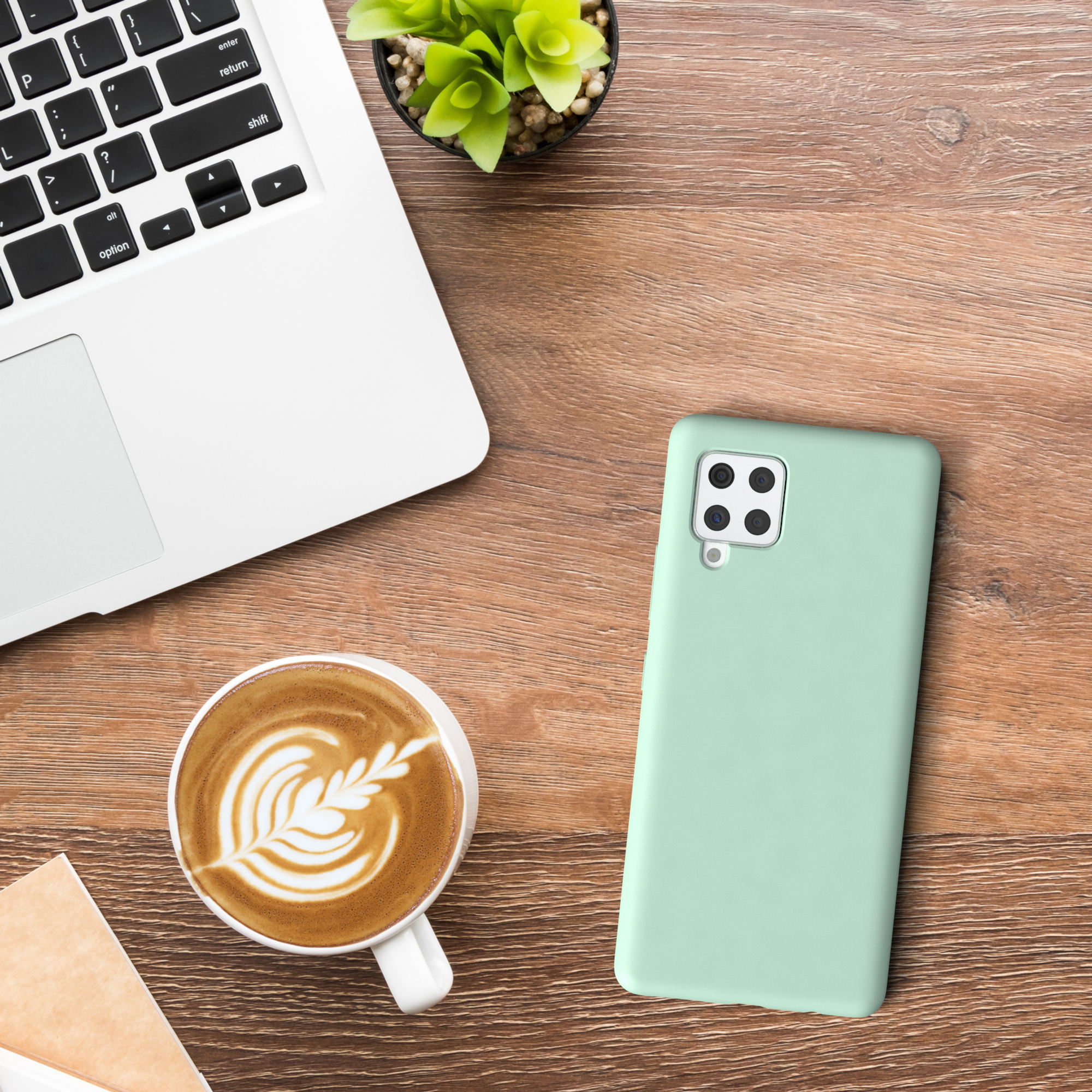 Laptop, Kaffeetasse und mintgrüne Handyhülle auf Holz.