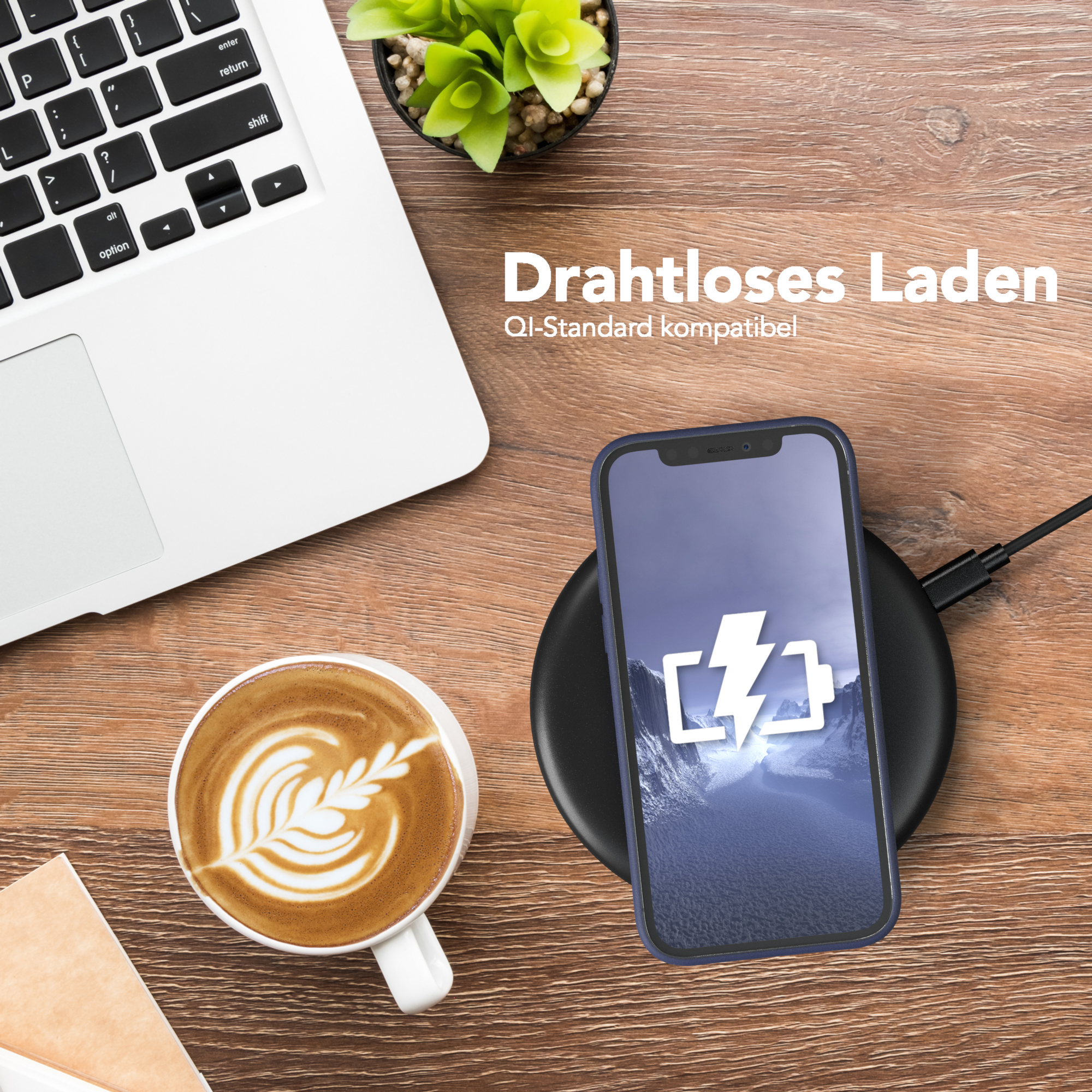 Ein Laptop, ein Telefon auf einem kabellosen Ladegerät, eine Kaffeetasse und eine Pflanze.