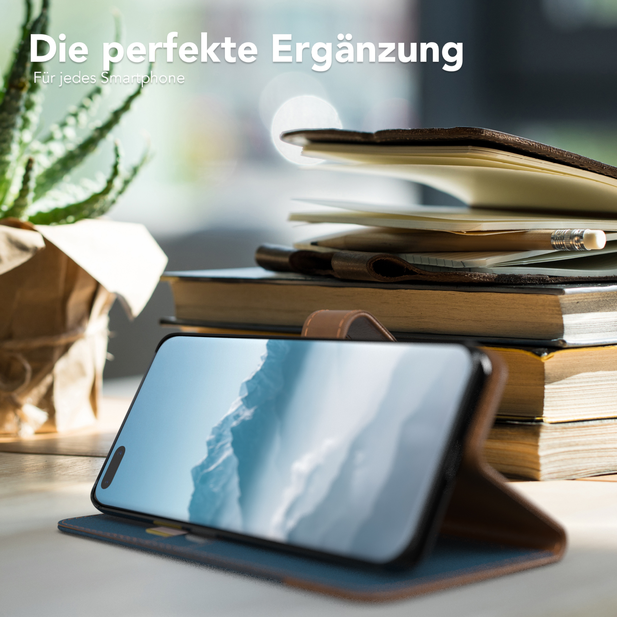 Ein Telefon in einer Hülle im Folio-Stil liegt auf einem Tisch. Im Hintergrund sind Bücher und eine Pflanze.