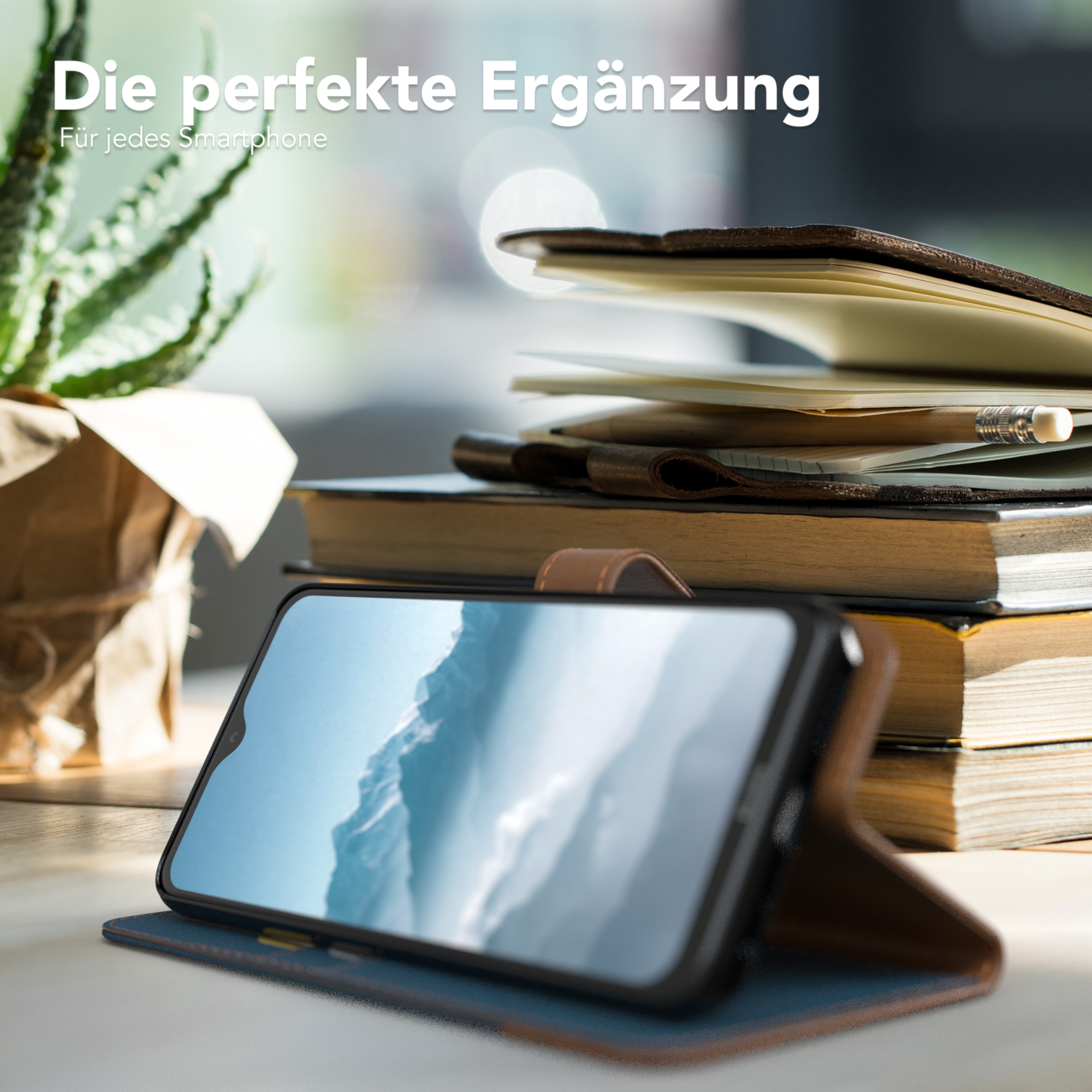 Smartphone in Lederhülle, mit Büchern und einer kleinen Pflanze im Hintergrund.