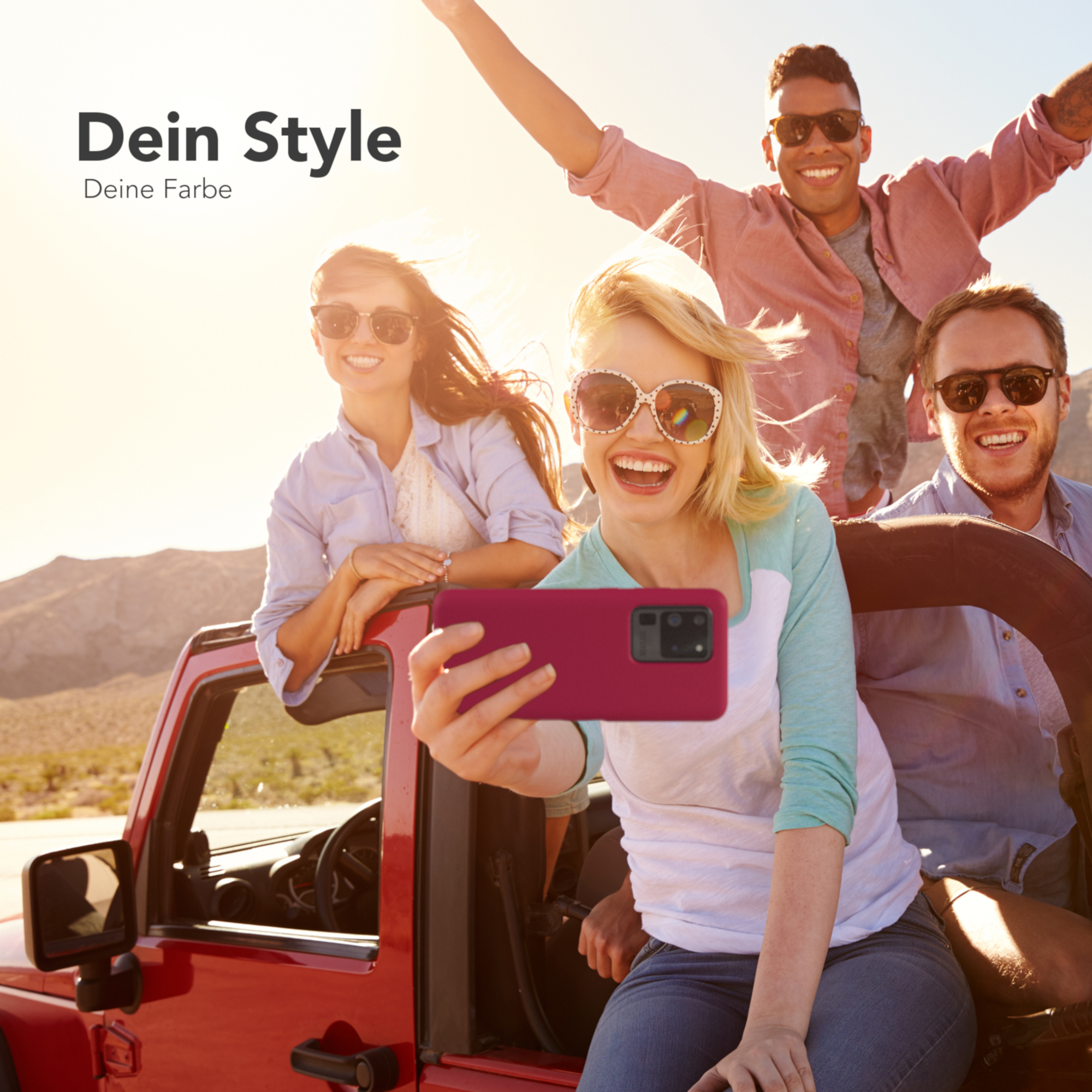 Vier Personen in einem roten Jeep machen ein Selfie mit einer rosa Handyhülle. Sonniger Hintergrund.