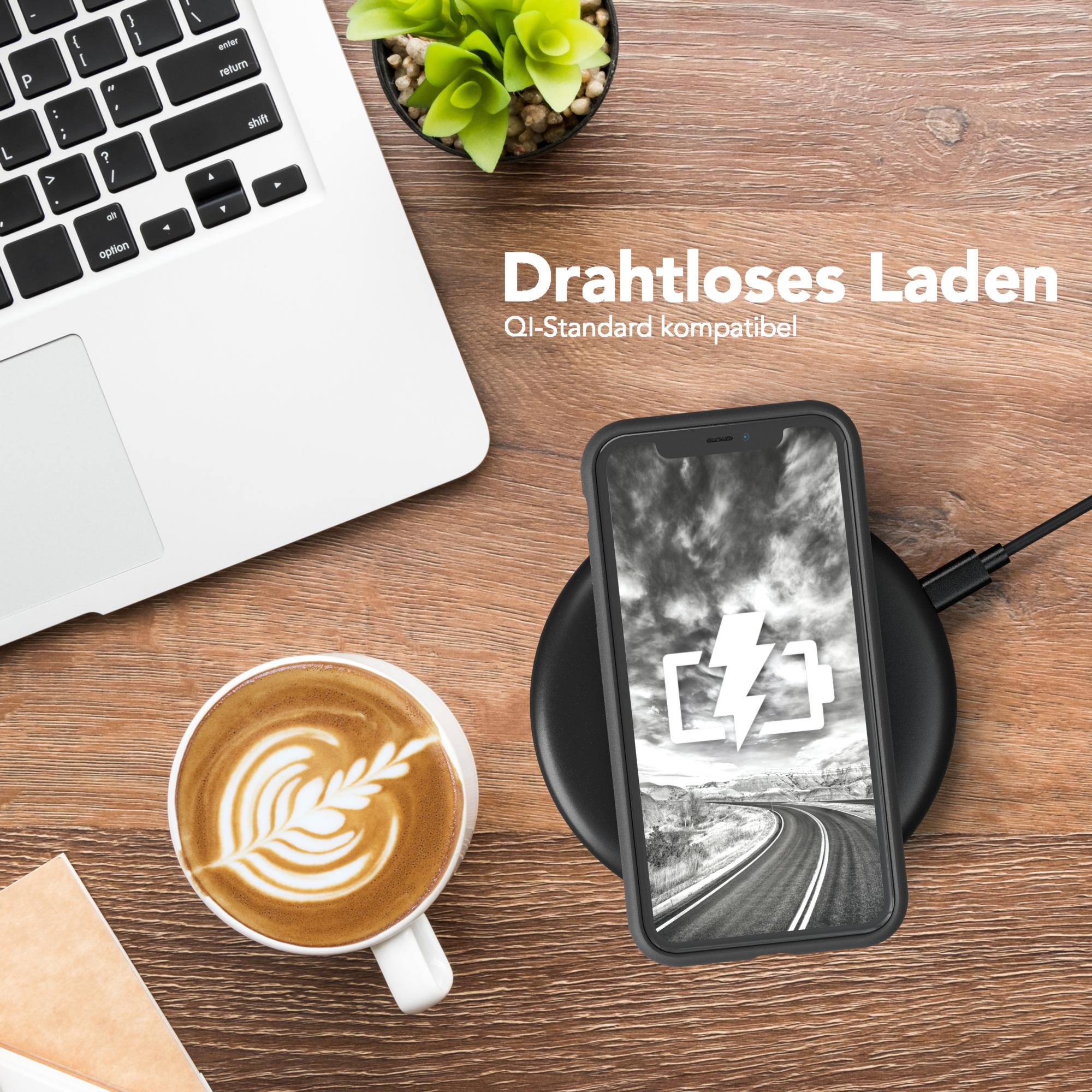 Telefon wird drahtlos auf einem Pad aufgeladen, neben einem Laptop, einer Tasse Kaffee und einer Pflanze.