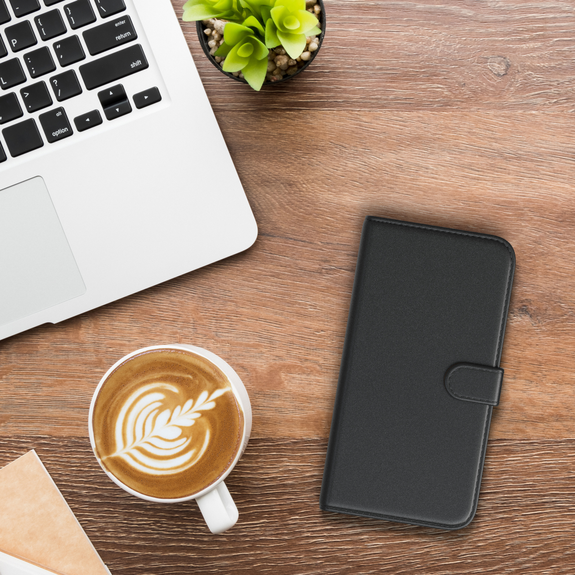 Laptop, eine Tasse Kaffee und eine Handyhülle auf einem Holztisch.