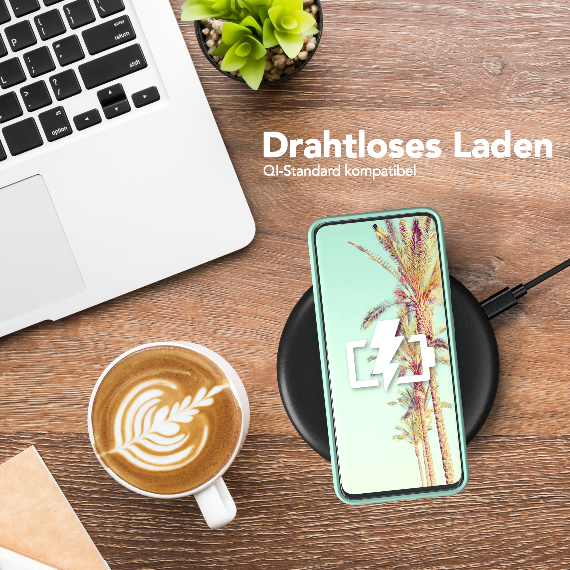Telefon in tealfarbener Hülle auf kabellosem Ladegerät. Tasse Kaffee und Laptop im Hintergrund.