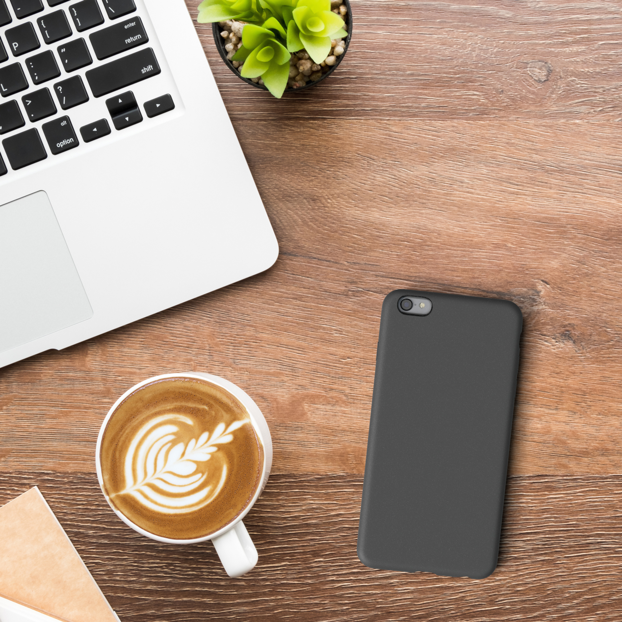 Laptop, Kaffee, Pflanze, Handyhülle auf einem Holztisch.