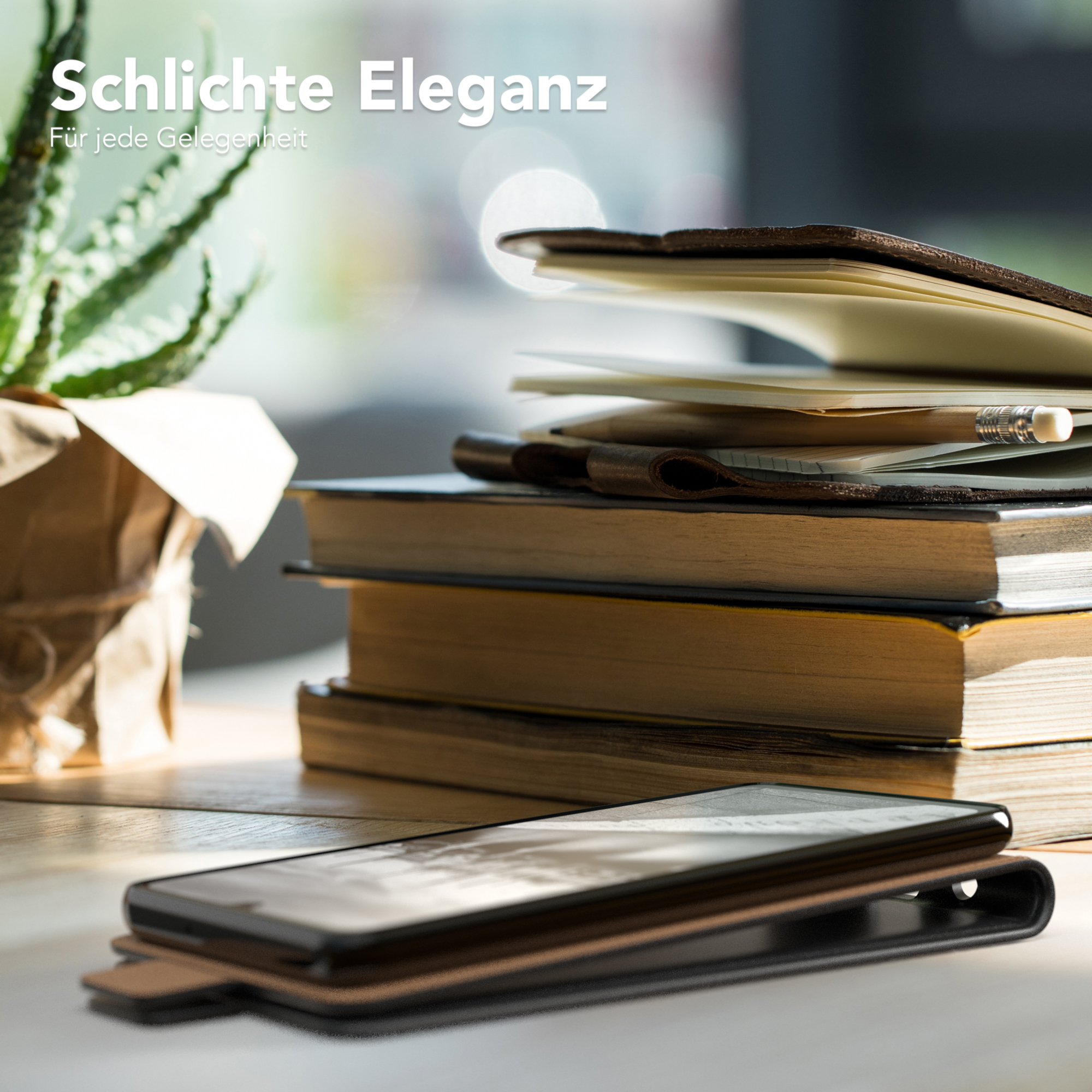Eine Handyhülle liegt auf einem Schreibtisch mit Büchern, einer Pflanze und einem Bleistift. Das Telefon liegt auf der Hülle.
