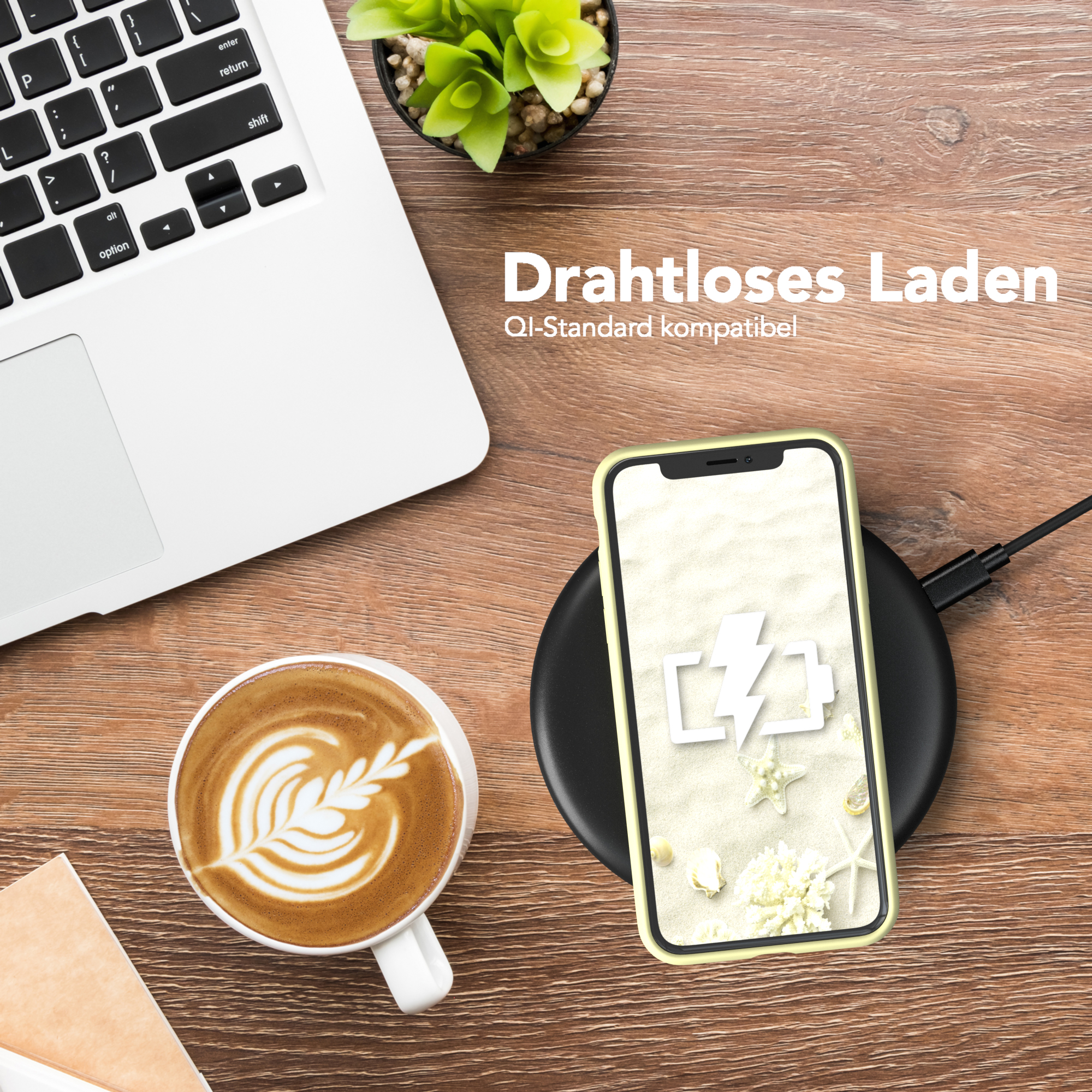Laptop, Kaffee mit Kunst, Telefon auf Ladegerät. Das Telefon zeigt ein Batteriesymbol.