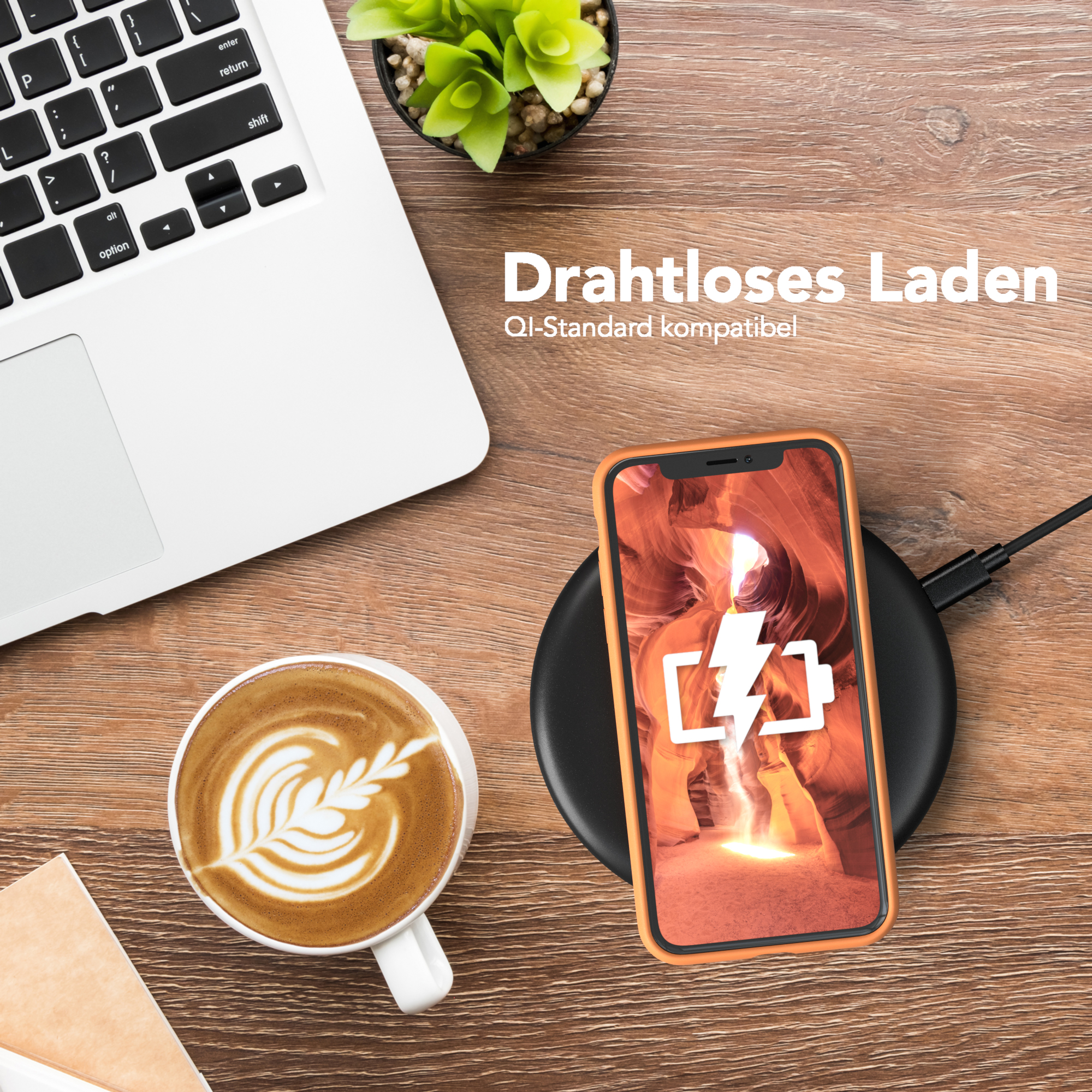 Laptop, Kaffee mit Latte Art und ein Telefon mit orangefarbener Hülle auf einem Holztisch. Kabelloses Laden.