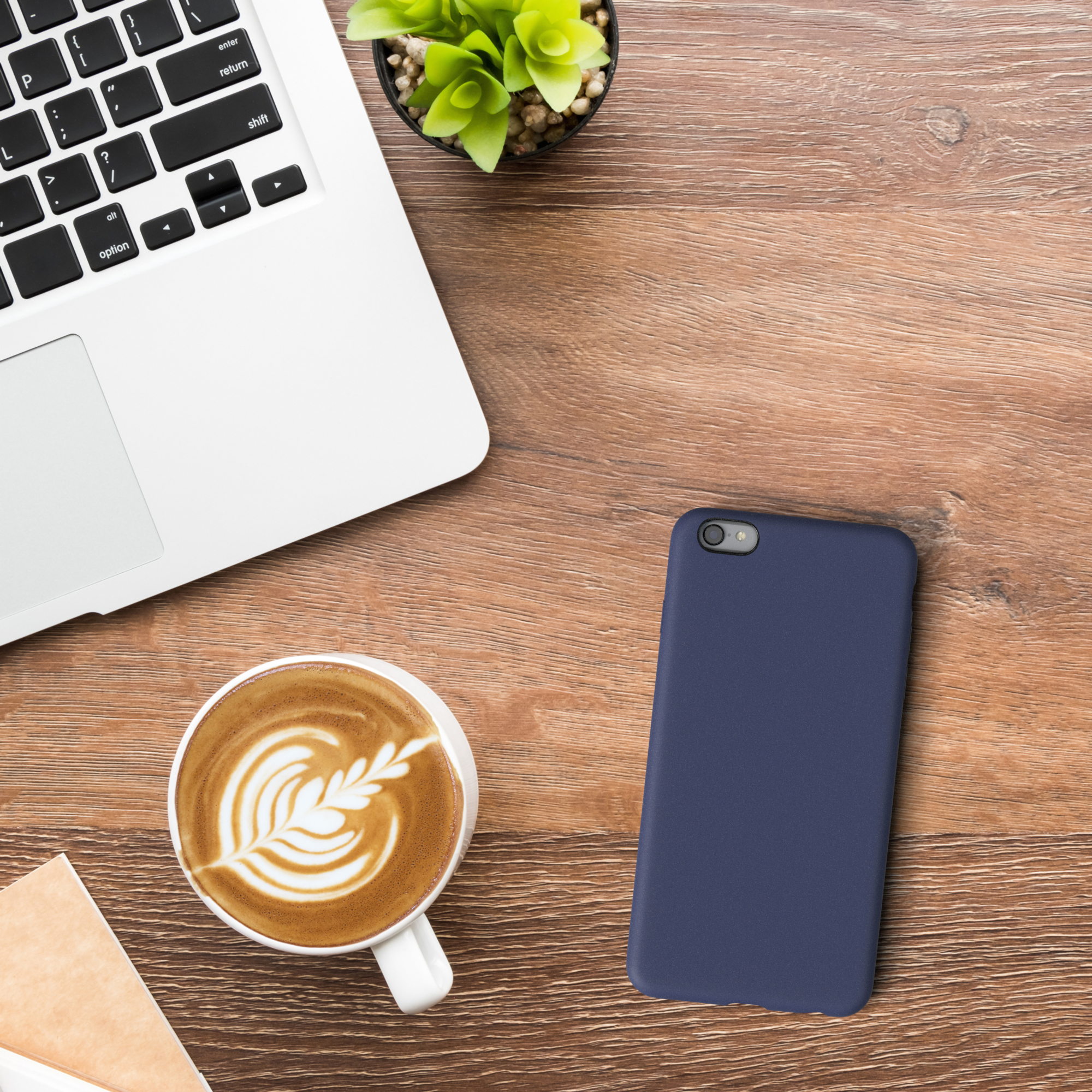 Blaue Handyhülle neben Laptop, Kaffee und Pflanze.