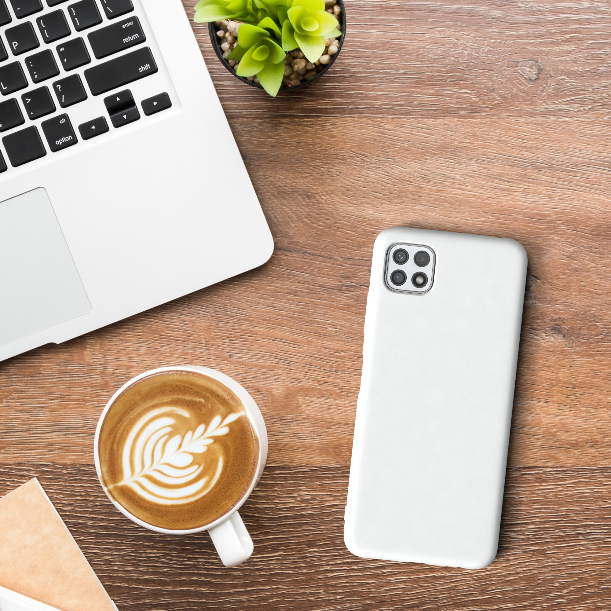 Laptop, Kaffee mit Latte Art, weißes Telefon und kleine Pflanze auf Holztisch.