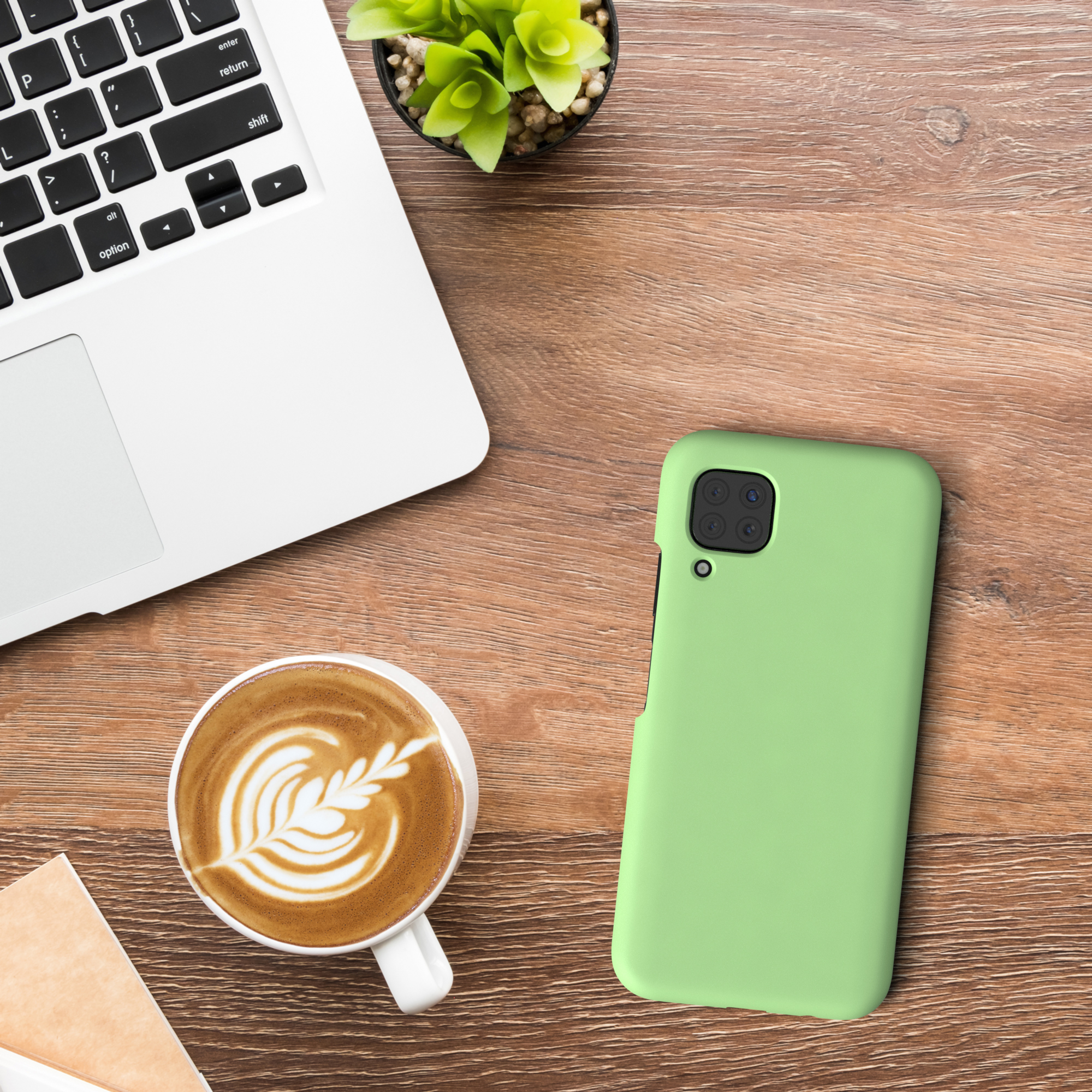 Telefon in einer grünen Hülle auf einem Holztisch, neben einer Tasse Kaffee und einem Laptop.