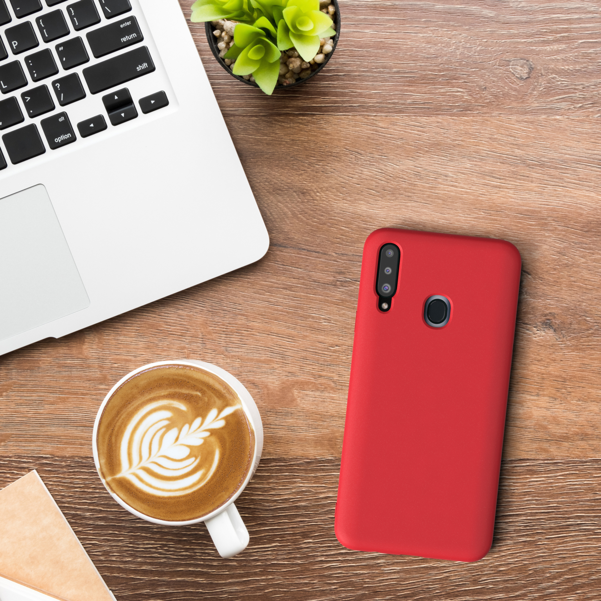 Laptop, Kaffee mit Latte Art und eine rote Handyhülle auf einem Holztisch. Draufsicht.