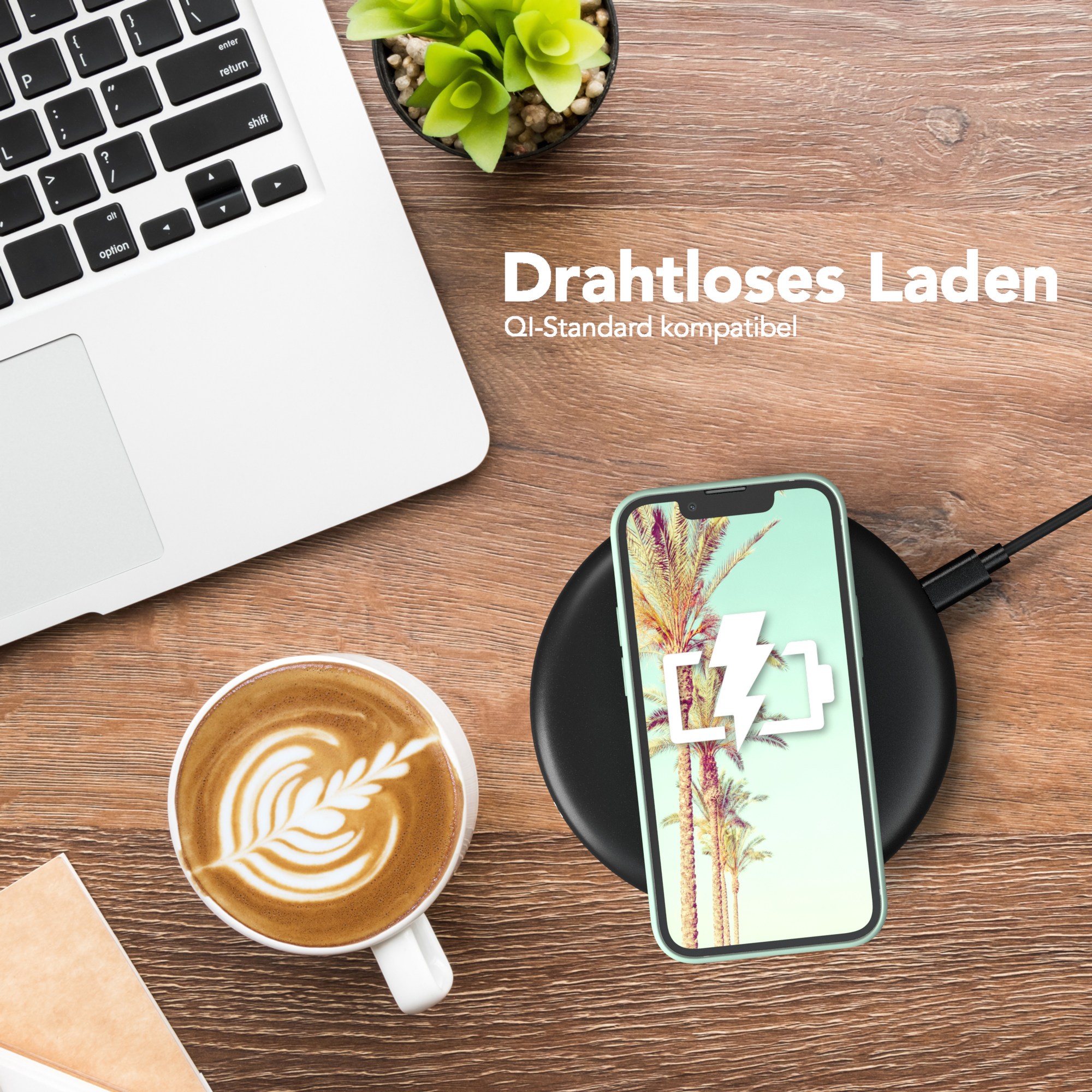 Laptop, Kaffee mit Kunst, Telefon auf Ladegerät. Das Telefon zeigt ein Batteriesymbol.