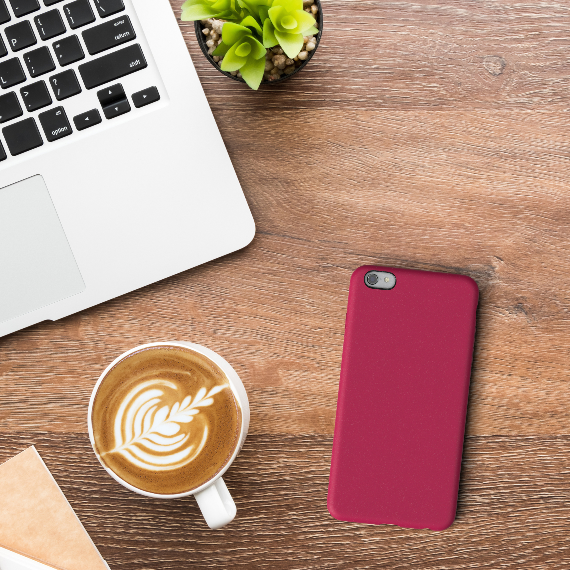 Draufsicht: Laptop, Kaffee mit Latte Art und rote Handyhülle.