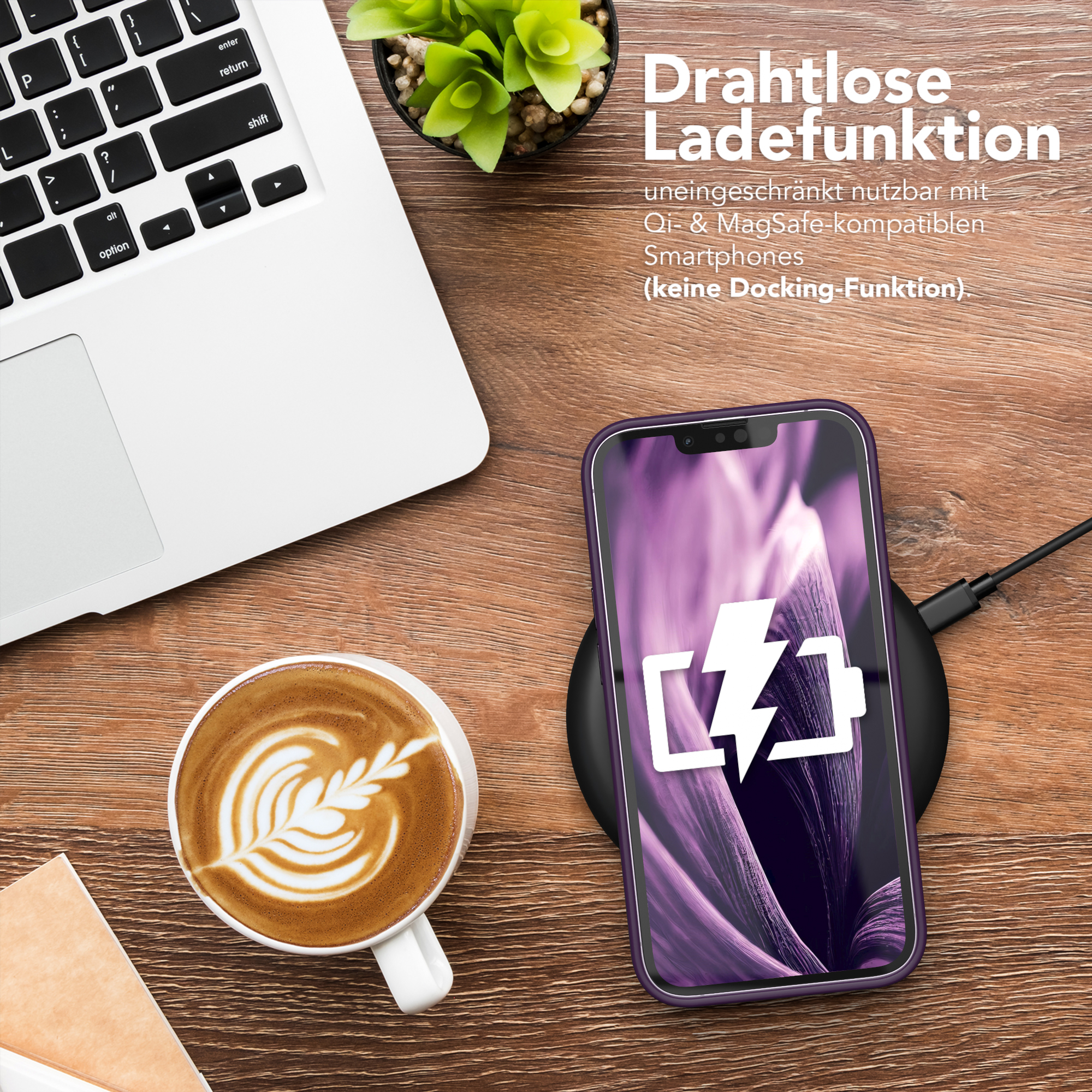 Ein Telefon, das drahtlos auf einem Pad geladen wird, neben einem Laptop und einer Kaffeetasse.