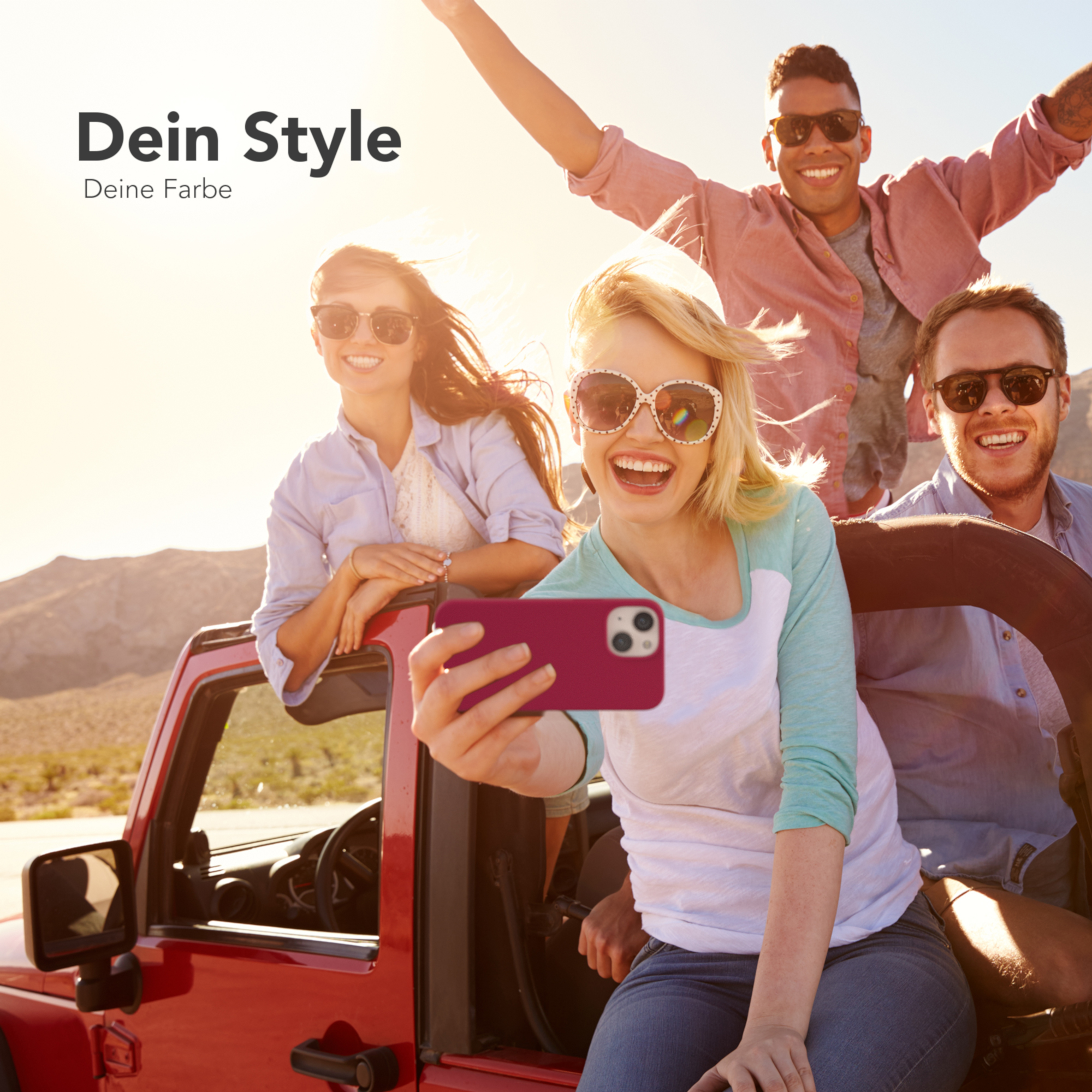 Vier Personen in einem roten Jeep machen ein Selfie mit einer rosa Handyhülle und lächeln in der Sonne.