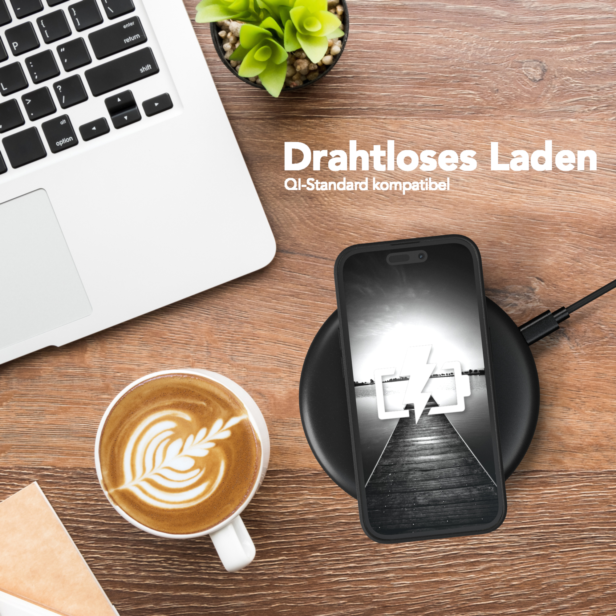 Ein Laptop, eine Tasse Kaffee, ein kabellos ladendes Telefon. Das Telefon zeigt ein Ladesymbol.