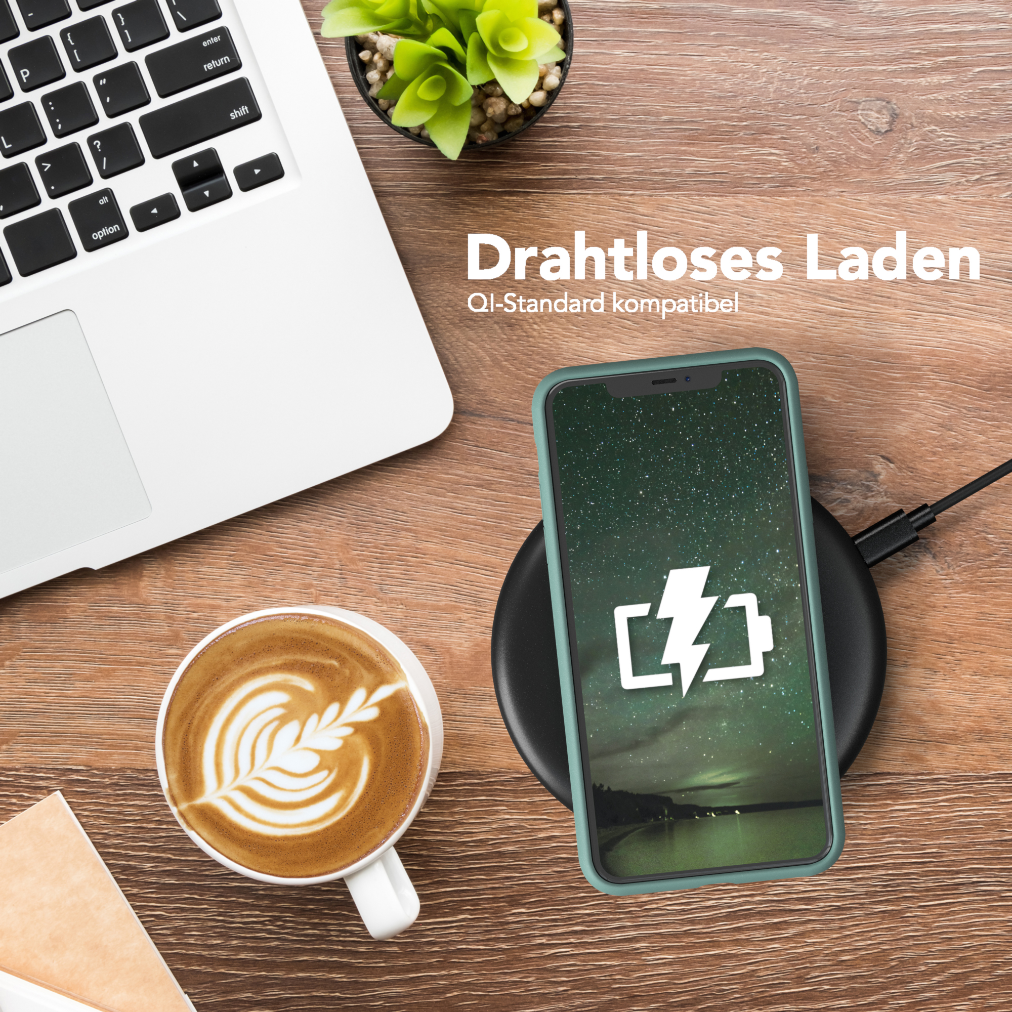 Telefon auf kabellosem Ladegerät. Kaffee, Laptop und Pflanze vorhanden.