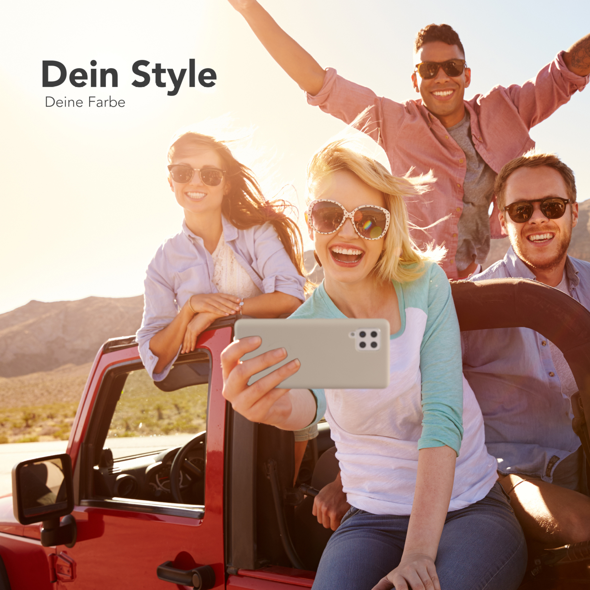 Eine Gruppe von vier Personen in einem roten Jeep, die ein Selfie mit einem Telefon machen. Der Hintergrund zeigt Landschaft.