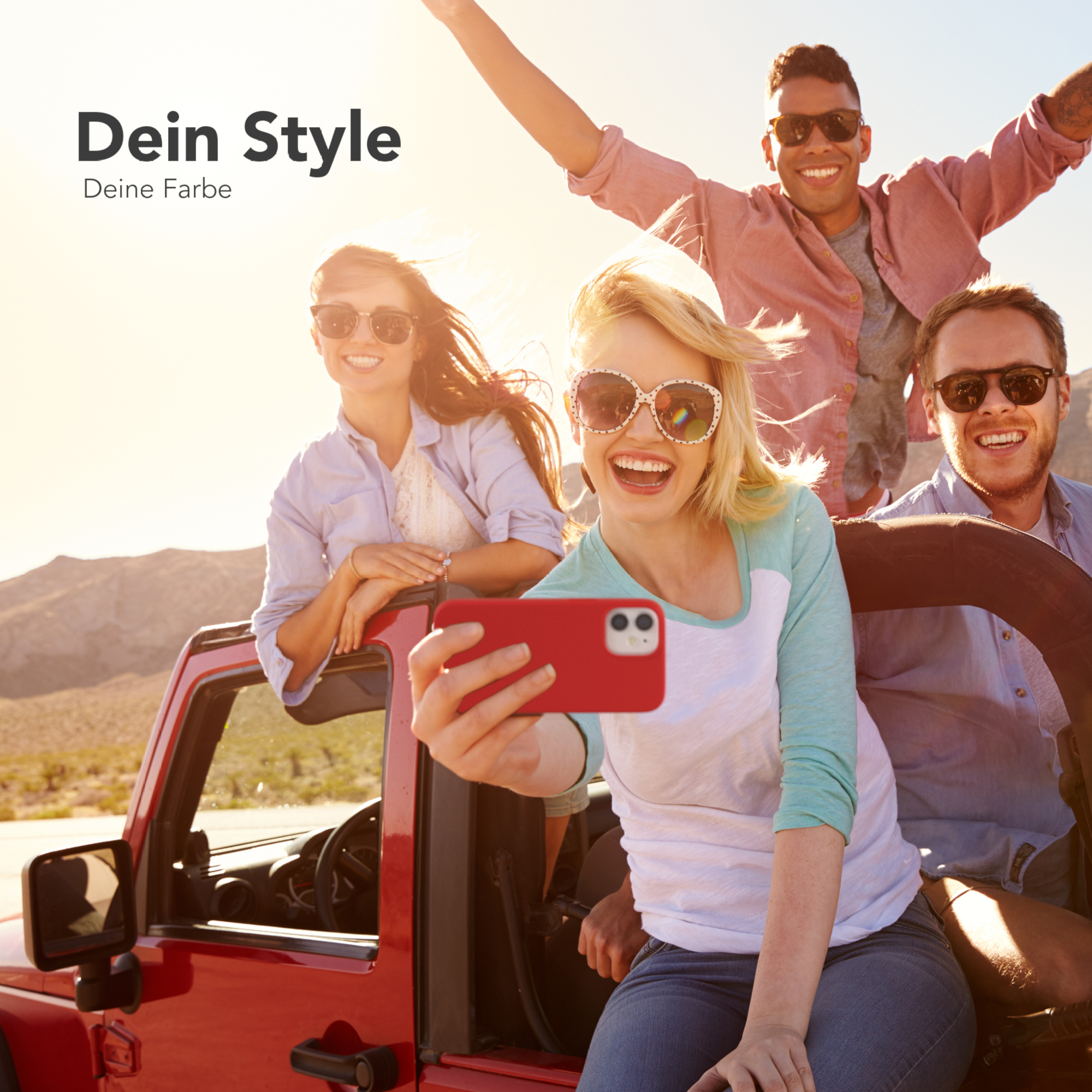 Gruppe von Freunden in einem roten Jeep, die ein Selfie machen. Frau hält Telefon mit roter Hülle.
