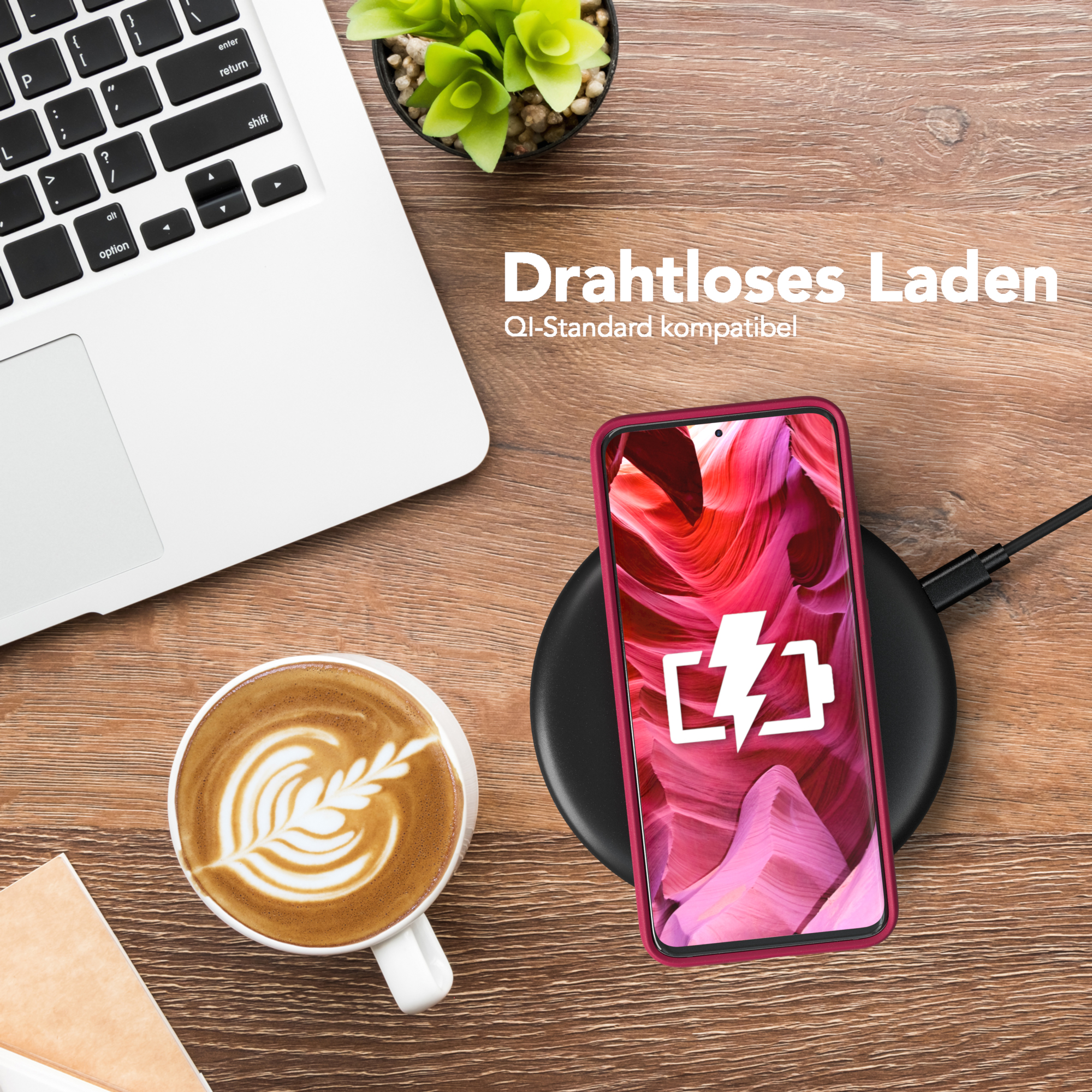 Ein Telefon in einer rosa Hülle, das auf einem kabellosen Ladegerät geladen wird. Es gibt eine Tasse Kaffee und einen Laptop.