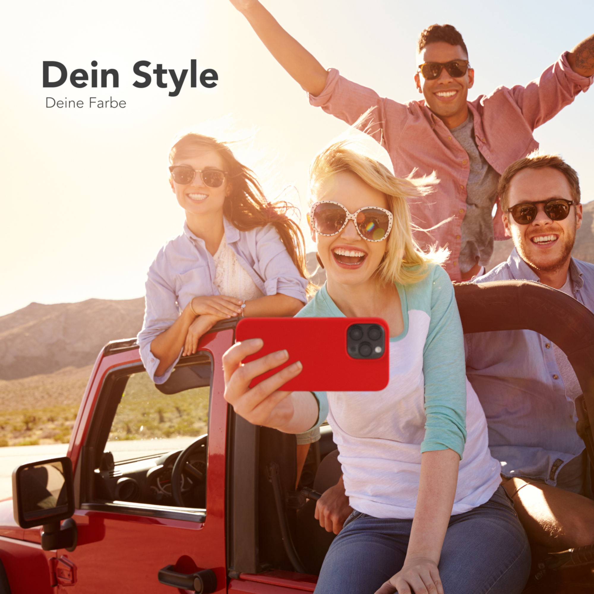 Vier Freunde in einem roten Jeep machen ein Selfie. Eine Frau hält eine rote Handyhülle. Sonne im Hintergrund.