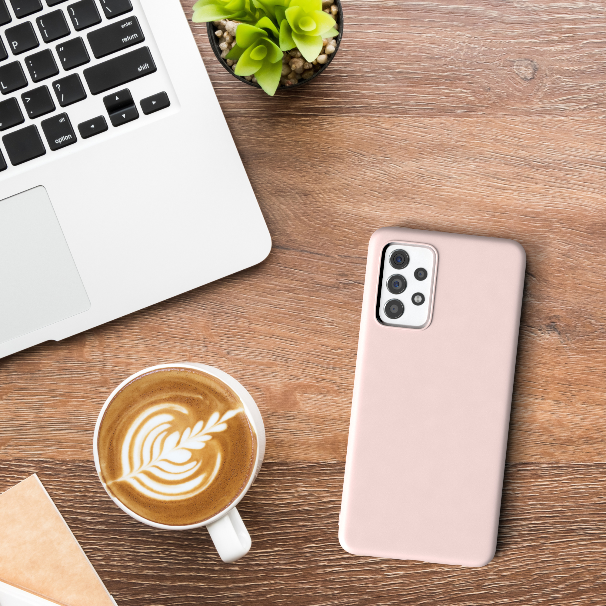 Laptop, Kaffee, eine Handyhülle und eine Pflanze auf einem Holztisch.