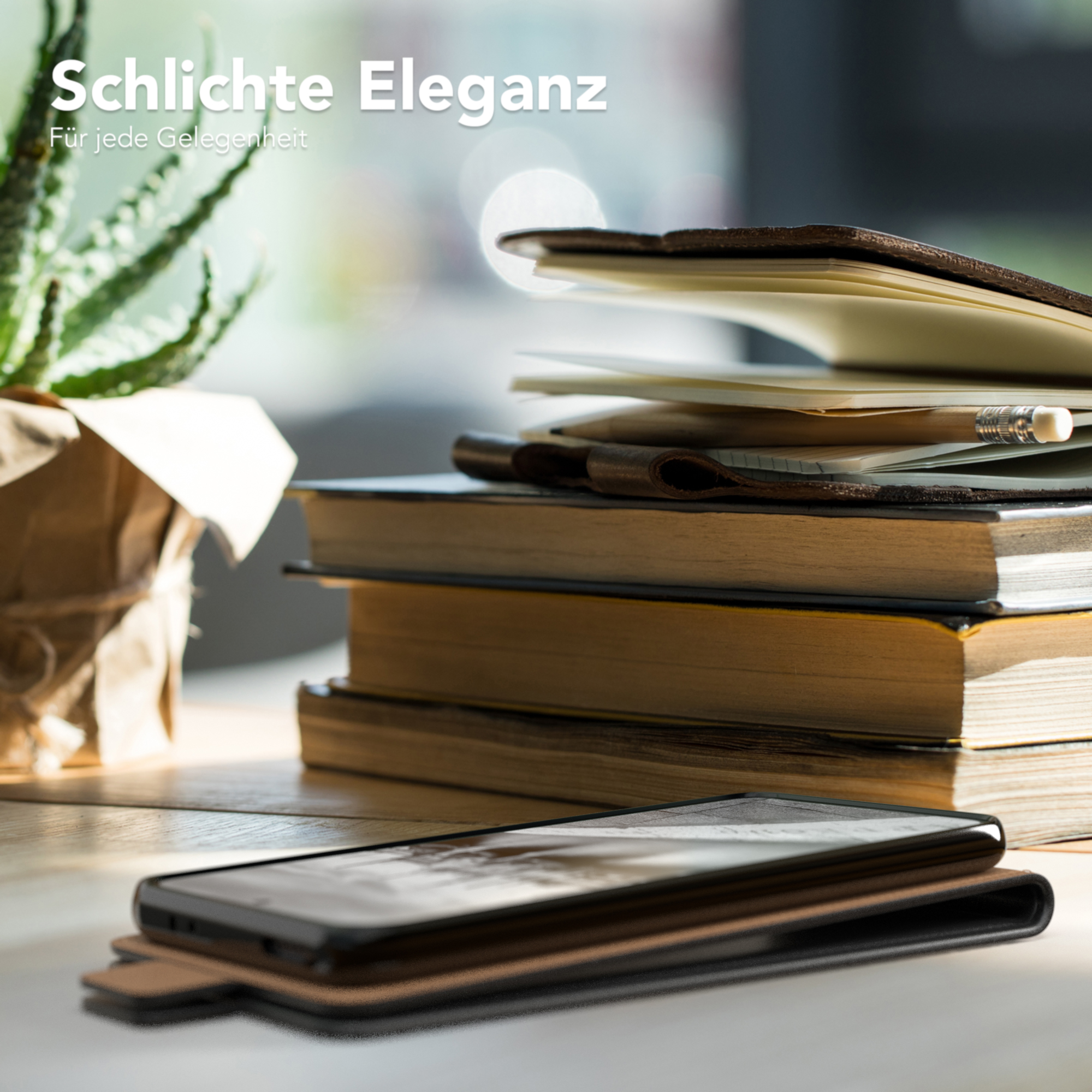 Handy in Lederhülle auf Tisch mit Büchern und Pflanze. Text: Schlichte Eleganz. Für jede Gelegenheit.