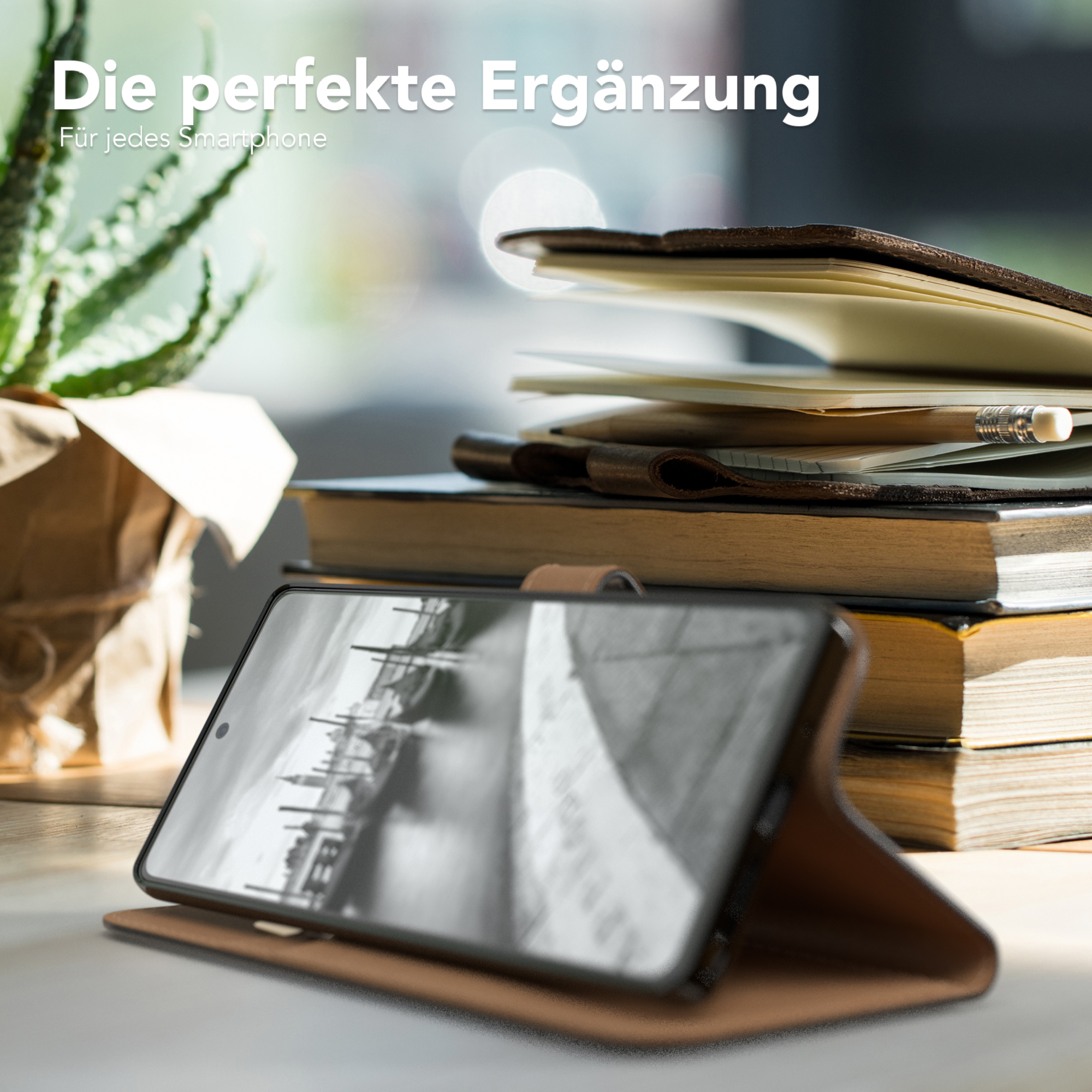 Handyhülle mit Telefon auf einem Tisch mit Büchern und einer Pflanze.