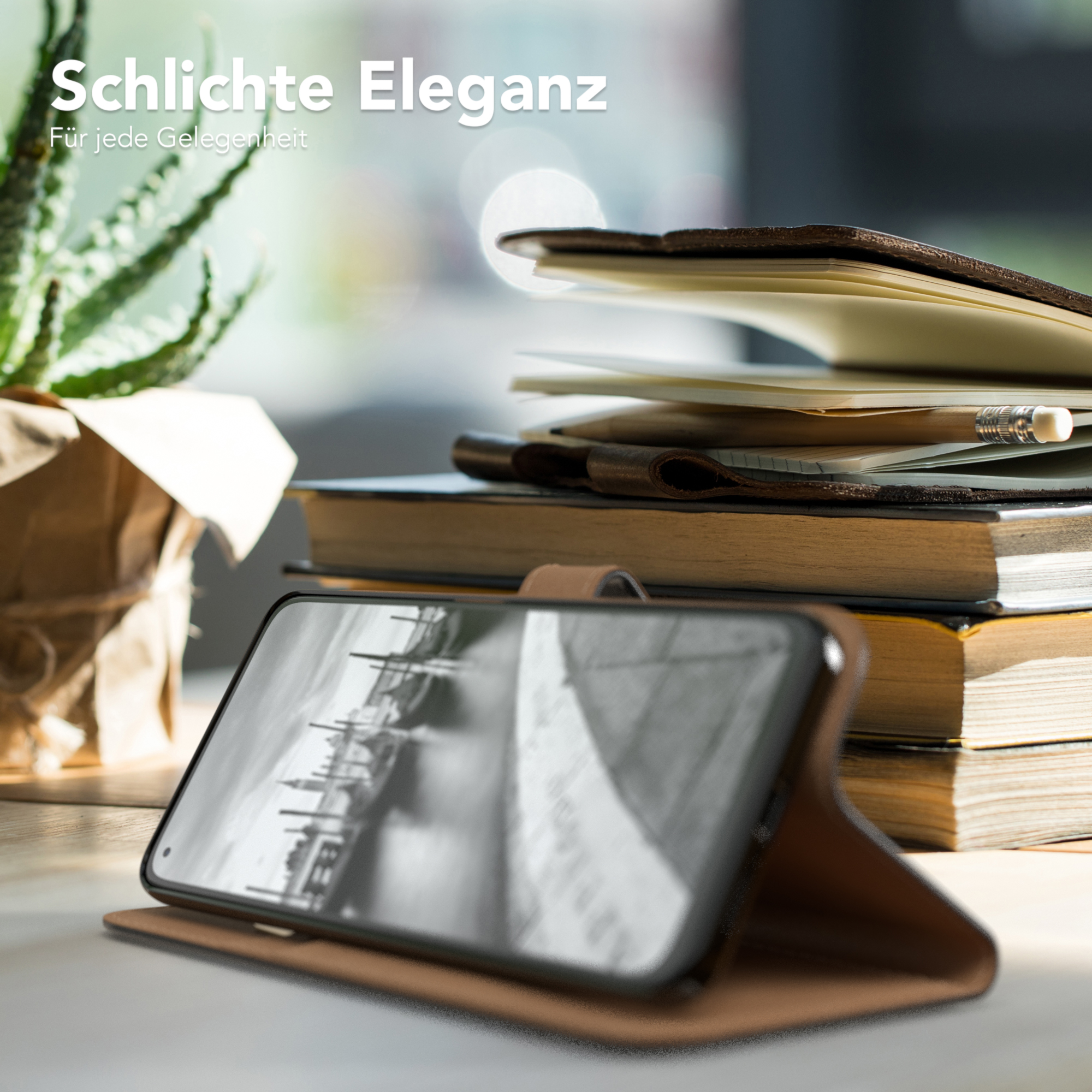Ein Telefon in einer Lederhülle, die auf einem Holztisch mit Büchern und einer Pflanze geöffnet ist.