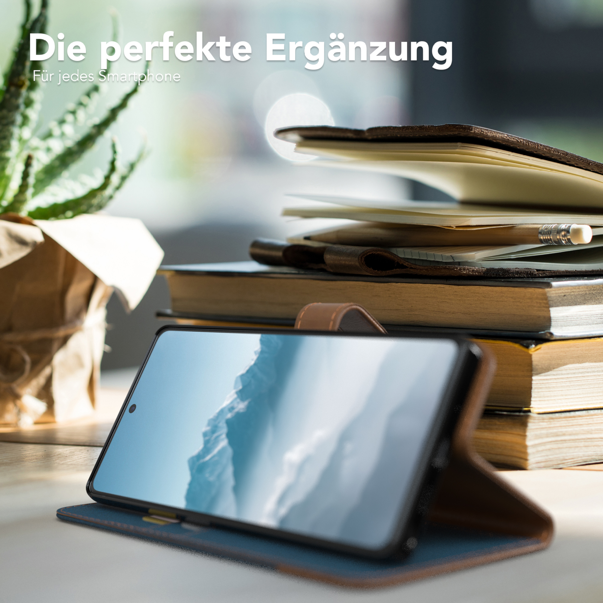 Telefon in blauer Hülle auf Schreibtisch mit Büchern und Pflanze. Text oben.