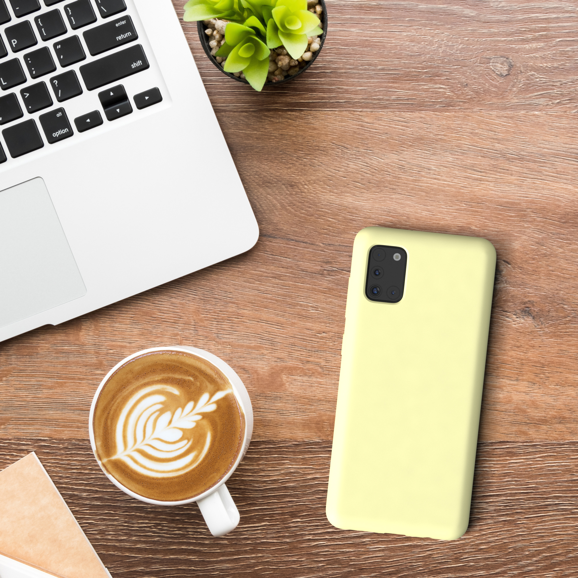 Ein Telefon auf einem Holztisch mit Laptop, Kaffeetasse und Pflanze.