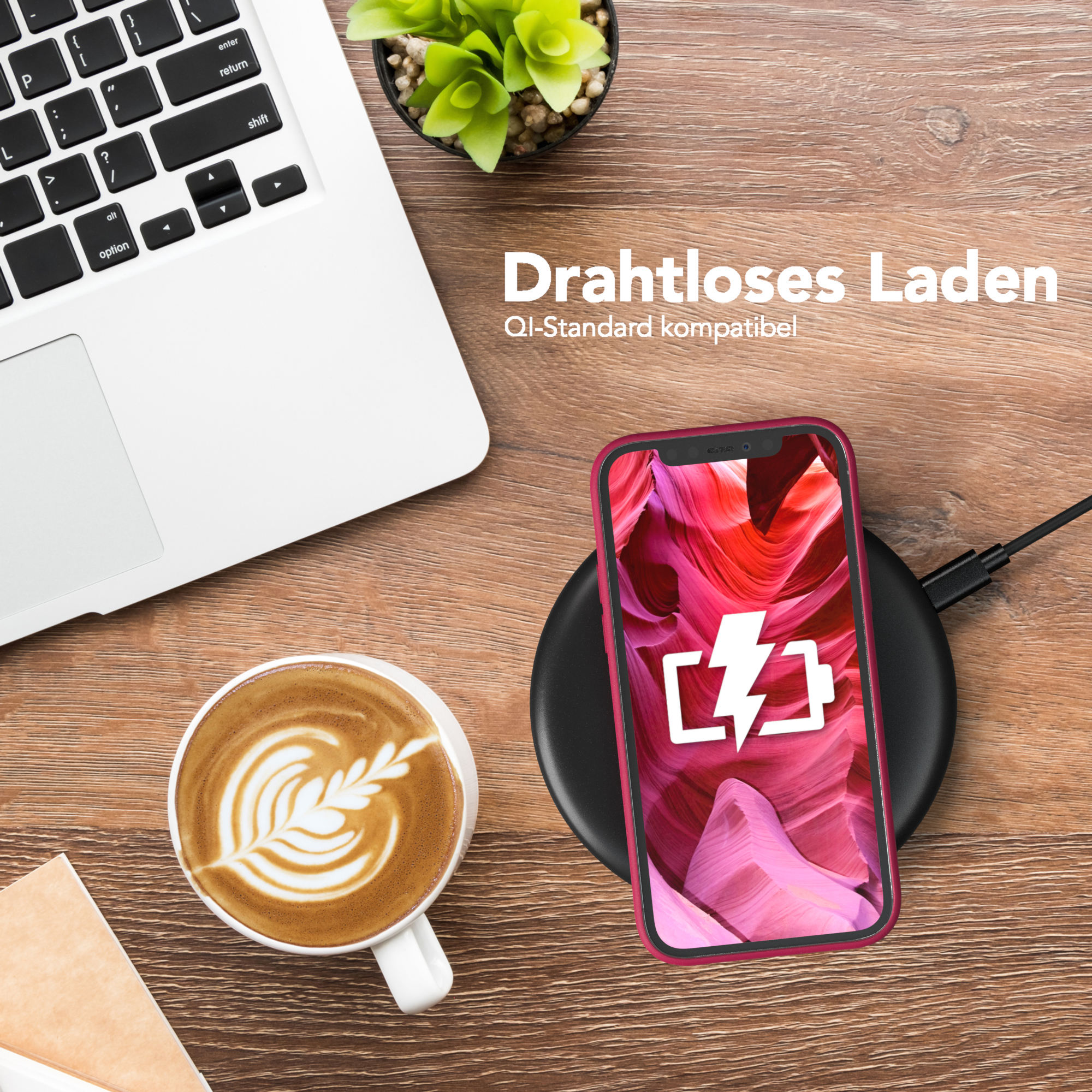 Telefon in roter Hülle wird kabellos geladen. Kaffee und Laptop stehen auf dem Holztisch.