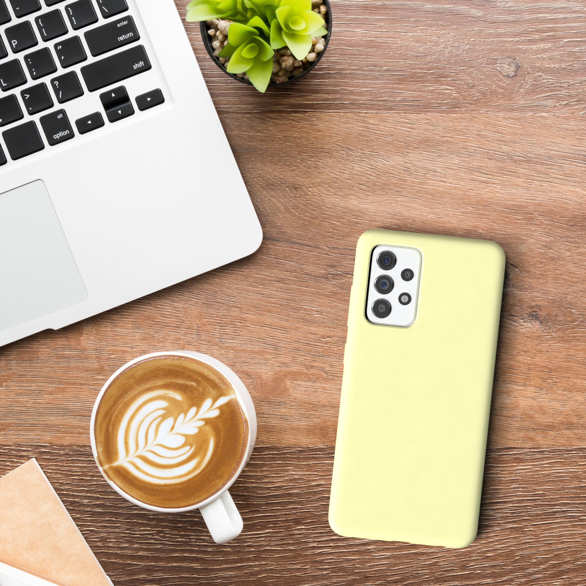 Laptop, Kaffee und gelbe Handyhülle auf Holztisch. Einfache Schreibtischanordnung.
